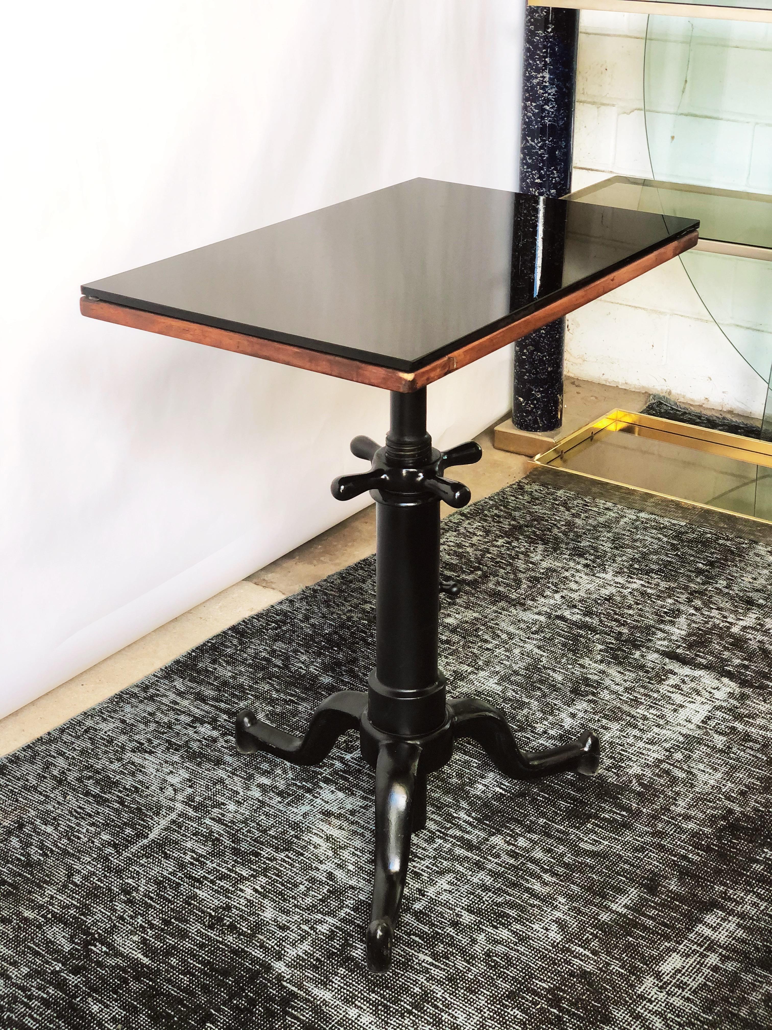 Vintage optometrist table. Heavy Industrial cast iron base that adjusts in height. Top swivels, or can be locked into place. Wooden top with thick black glass. Unknown maker.
Good condition,
circa 1940s. When adjusted height extends to 36.75