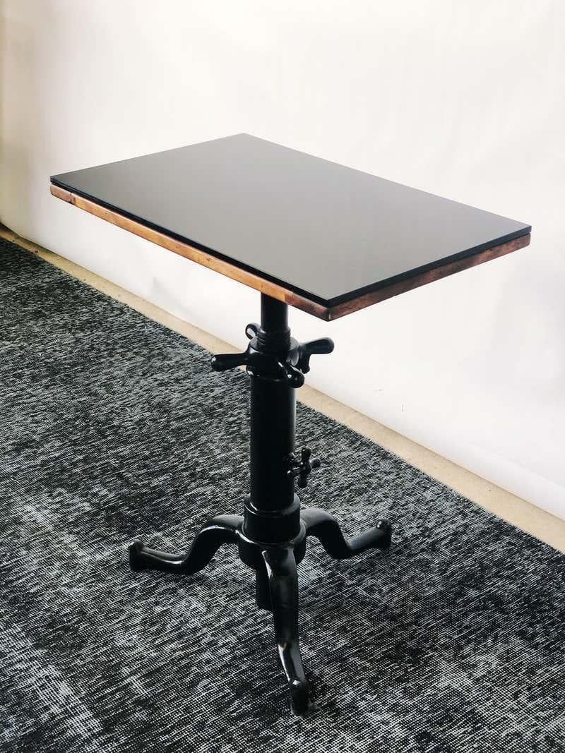 Vintage optometrist table. Heavy Industrial cast iron base that adjusts in height. Top swivels, or can be locked into place. Wooden top with thick black glass. Unknown maker.
Good condition,
circa 1940s. When adjusted height extends to 36.75.