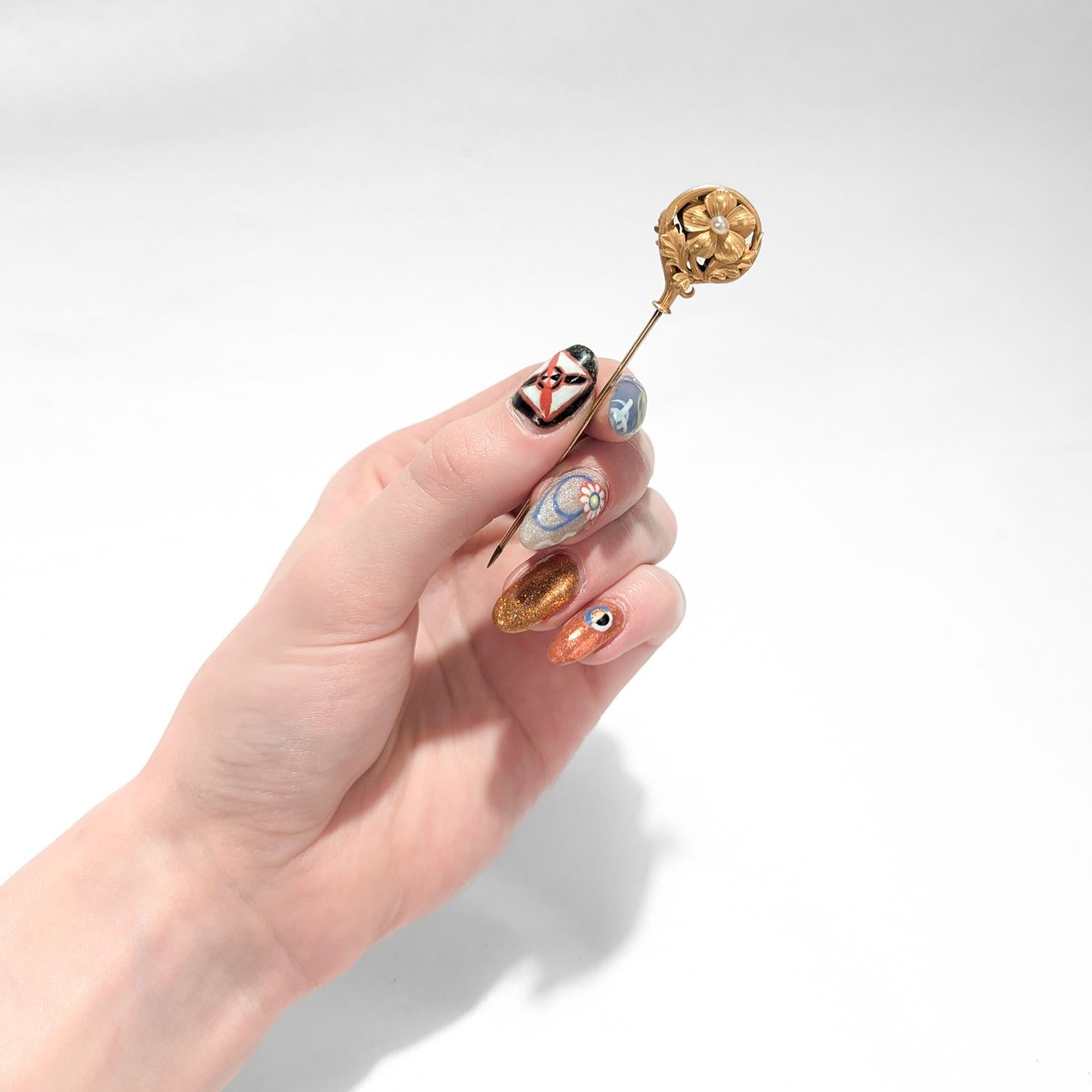 Une belle épingle à nourrice ancienne à double face convertie en épingle à chapeau.

Avec une partie supérieure en or jaune 14 carats et une tige en plaqué or.

Sous la forme d'une fleur de myosotis figurative avec un pistil perlé dans une couronne