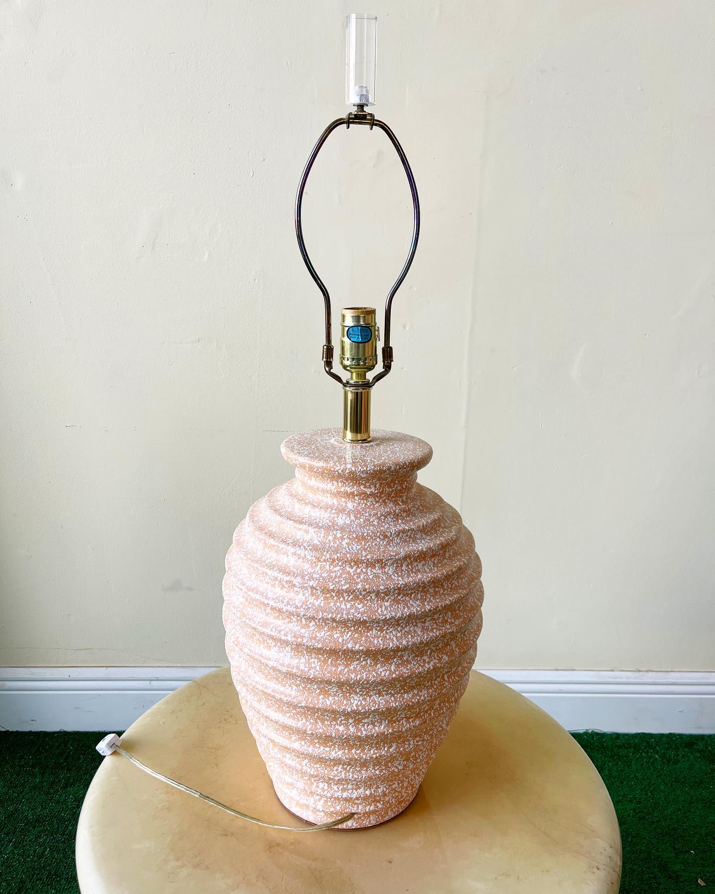 Unique orange and white speckled table lamp. Features ridges wrapping around the body of the lamp from the bottom to the top.