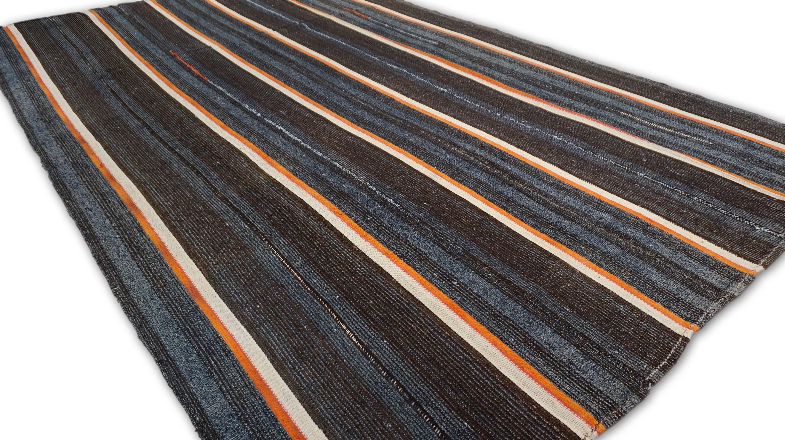 Este kilim vintage de lana presenta un llamativo motivo de rayas verticales en una armoniosa paleta de tonos naranja, azul, tostado y marrón. Su diseño atrevido pero refinado aporta un toque contemporáneo a la artesanía tradicional, lo que lo