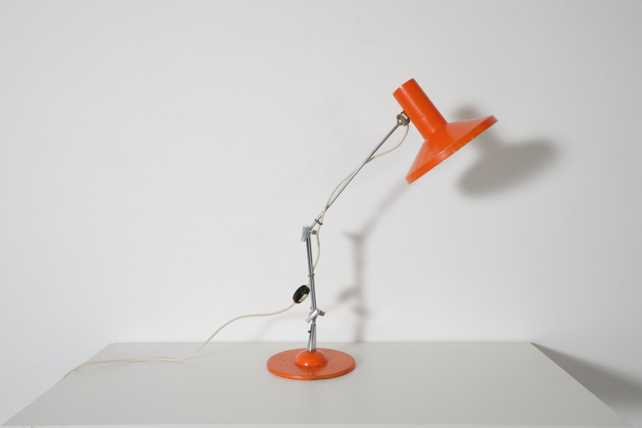 Mid-Century, multi-adjustable drafting table lamp with heavy metal base. Industrial architecture lamp with chrome stem and steel knobs for height and directional light adjustments. A stylish orange enameled table lamp perfect for a studio space or a