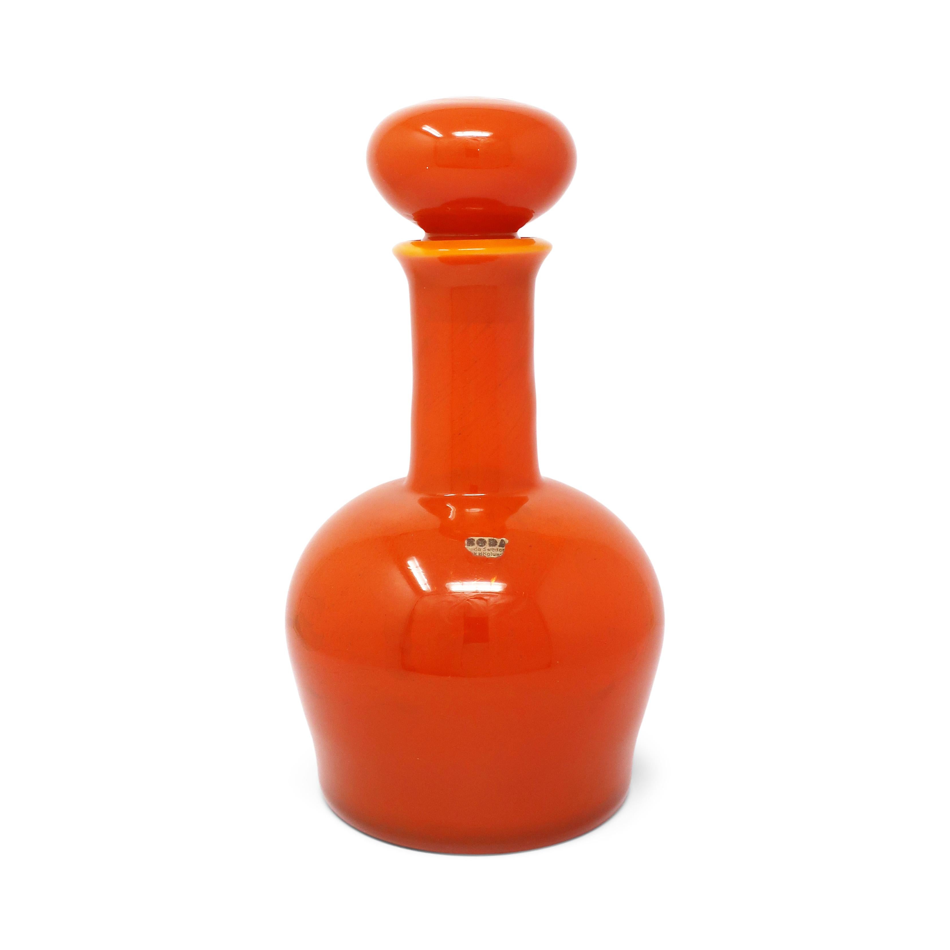 A beautiful Swedish modern orange art glass decanter with stopper by Erik Hoglund for Boda (now known as Kosta Boda).  A classic form designed by a master of the art glass craft and a pioneer of mid-century modern and Scandinavian modern design. 