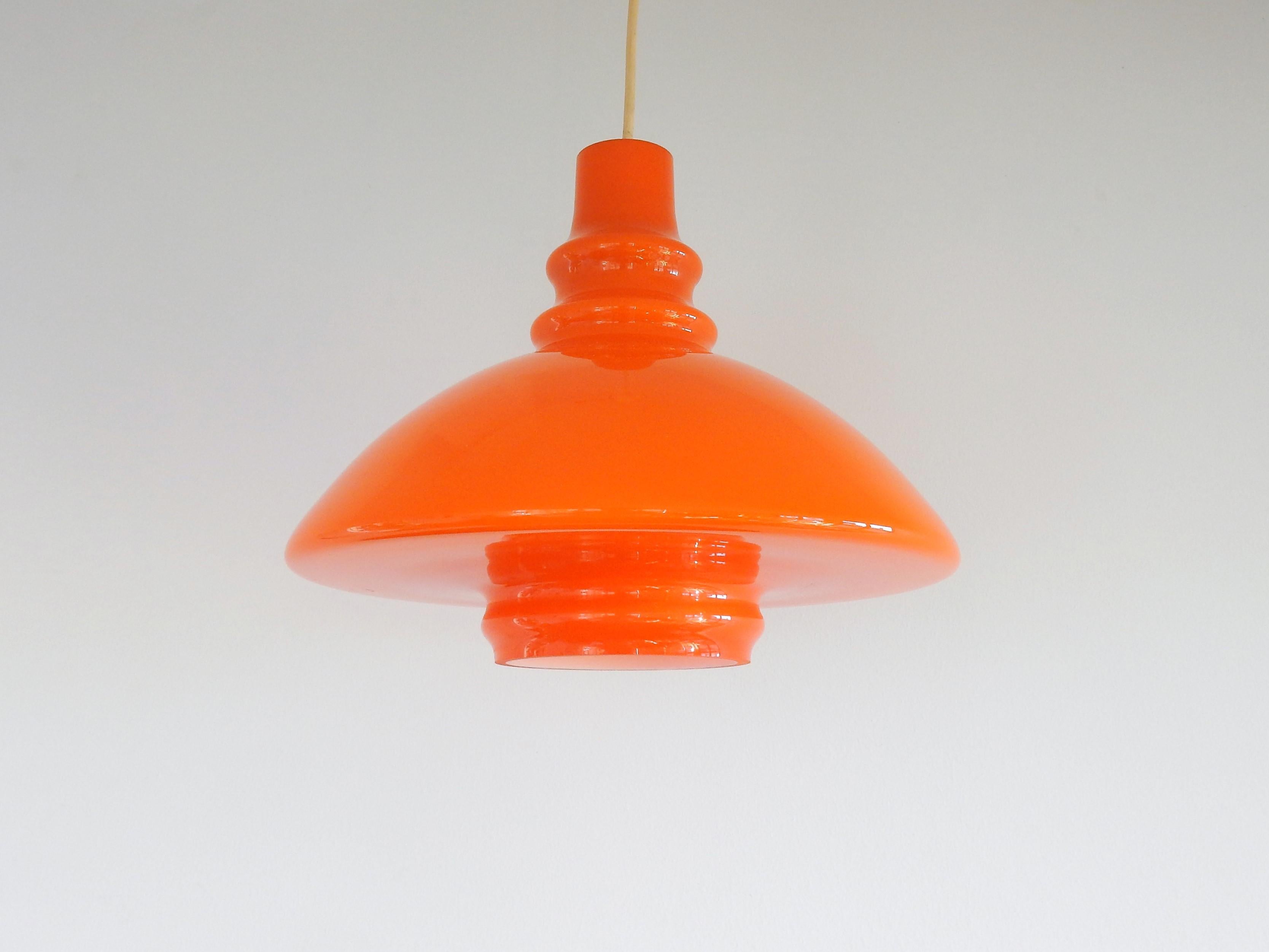 This vintage orange glass pendant lamp was imported from Germany. It has a beautiful shape that has similarities to the designs of Peill & Putzler. The bottom of this lamp is also covered with glass that gives a very pleasant lighting. It is in a