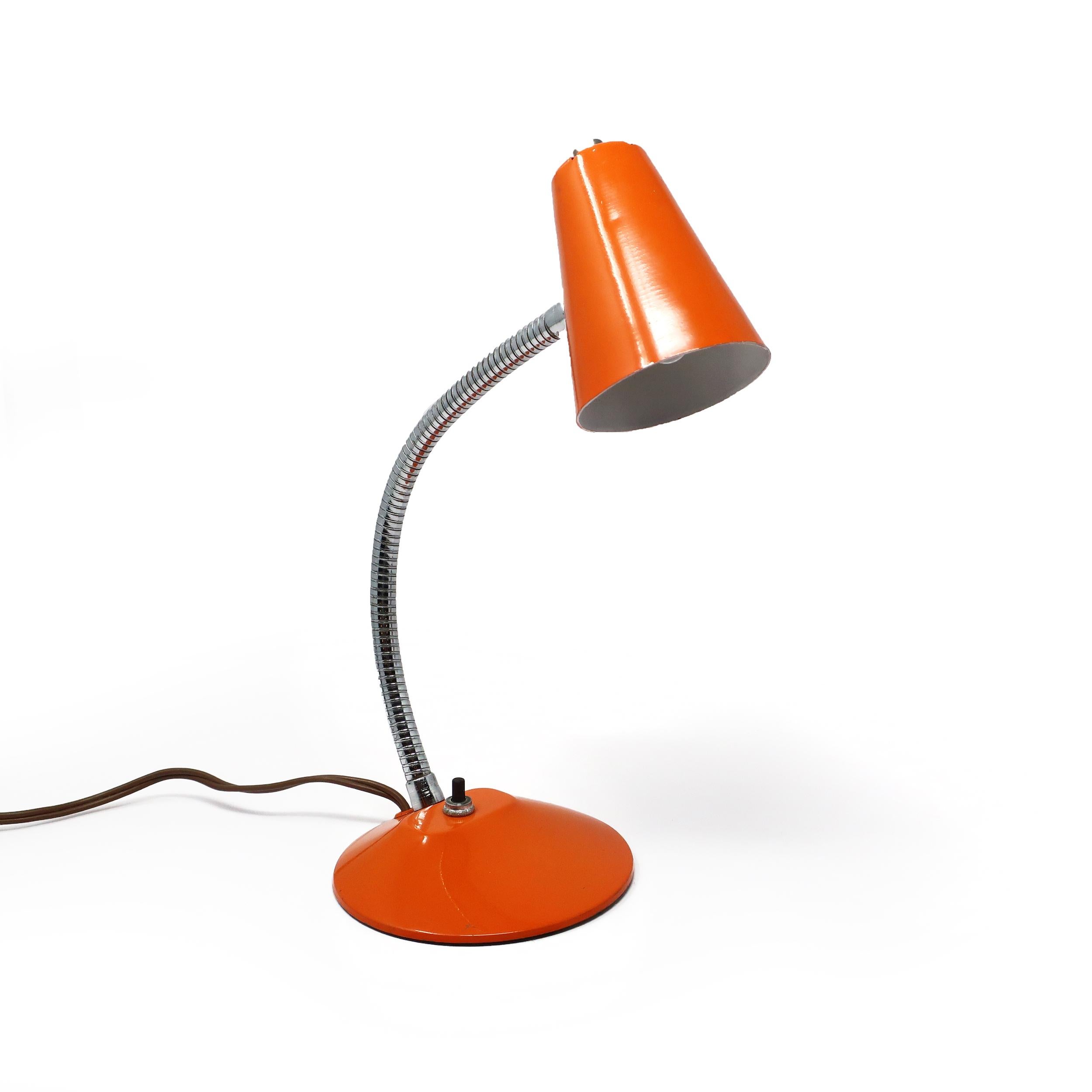 A vintage orange desk lamp with conical metal shade, round metal base, and chrome gooseneck stem. Has a push button on/off switch on the base. 

In very good vintage condition and includes a new LED lightbulb.

Measures: 5