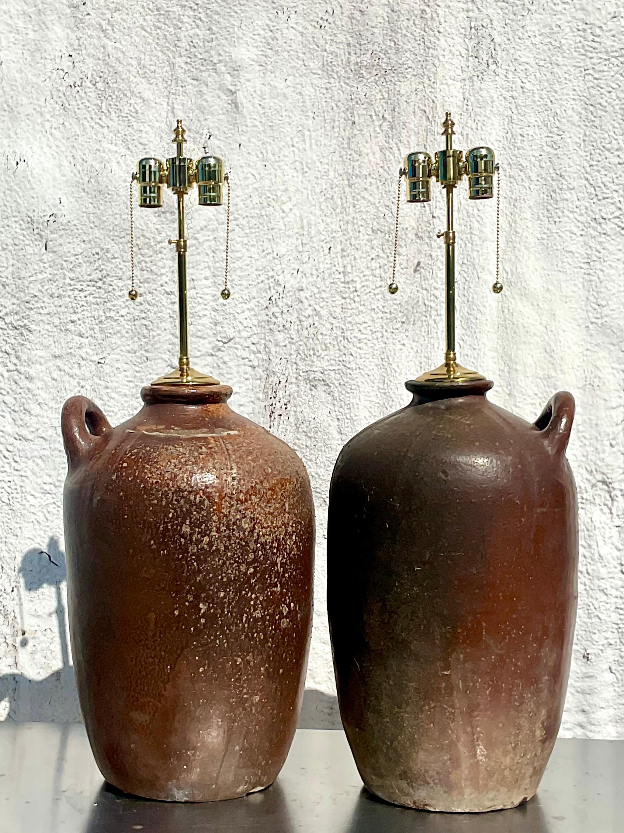 Incredible pair of vintage monumental water jug lamps. Old and with a patina to match. Just the most beautiful rustic finish. Two of the same jug, each with their own look. Totally restored with all new hardware and wiring. Acquired from a NY estate.