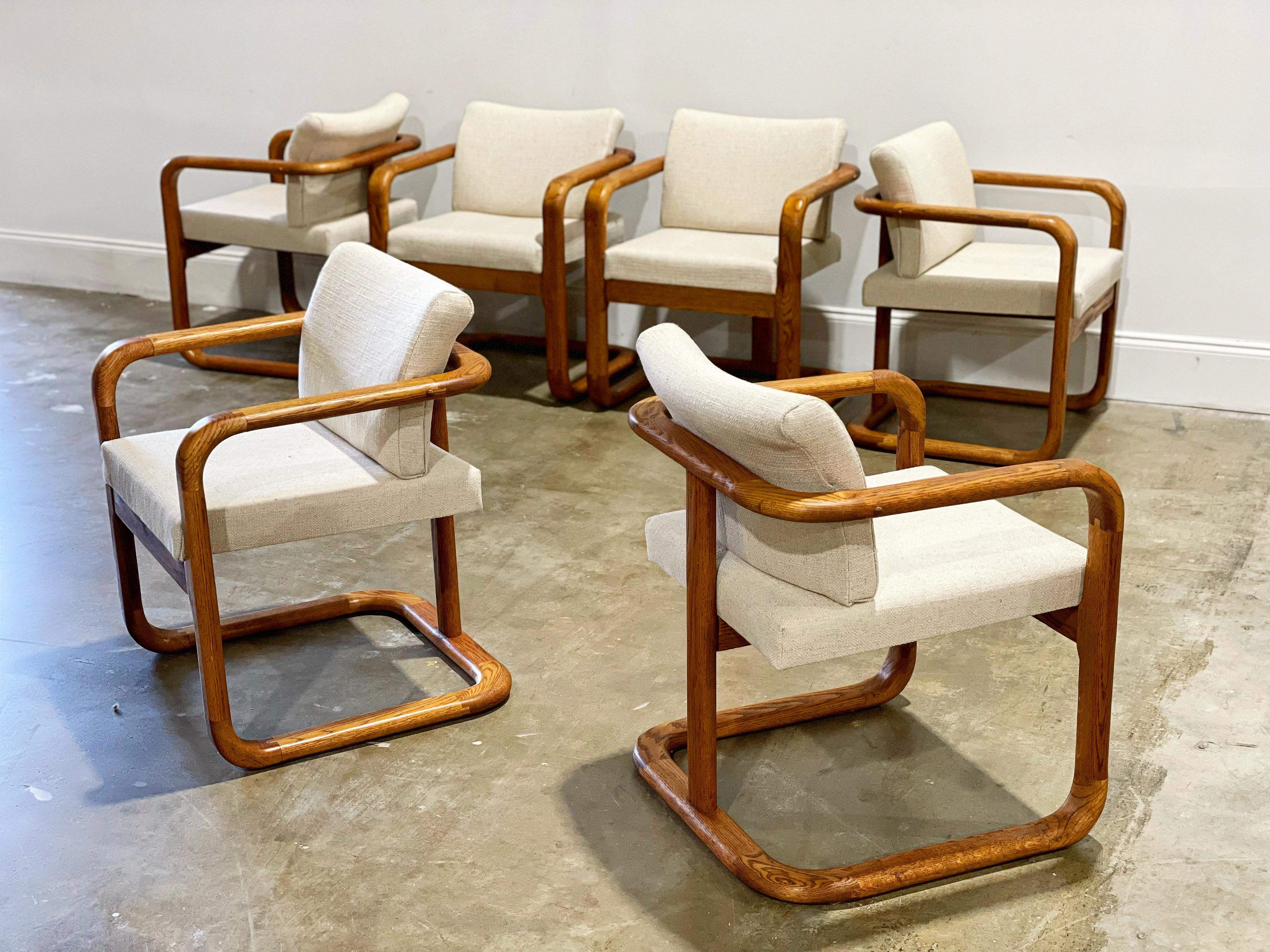 Sculpted bentwood oak dining chairs after Lou Hodges. This set of six is unique on the market. Stellar design and a gorgeous profile - perfect juxtaposition of shape and form. Upholstered seats and swivel backs provide maximum comfort with