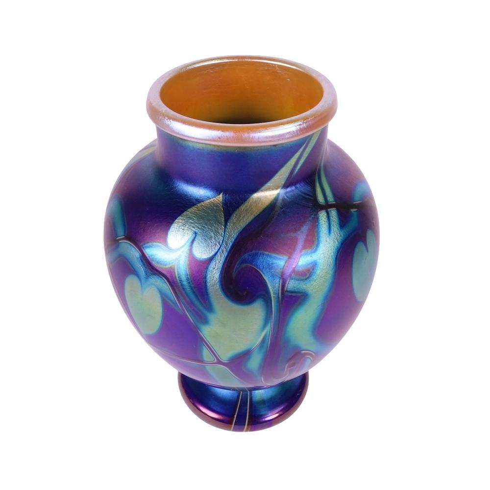 Presenting this outstanding Orient & Flume art glass vase. Vase is decorated with platinum hearts and platinum vines, known as a “heart and vine” design. The main color of this vase is blue with peacock iridescence, featuring a gold iridescent