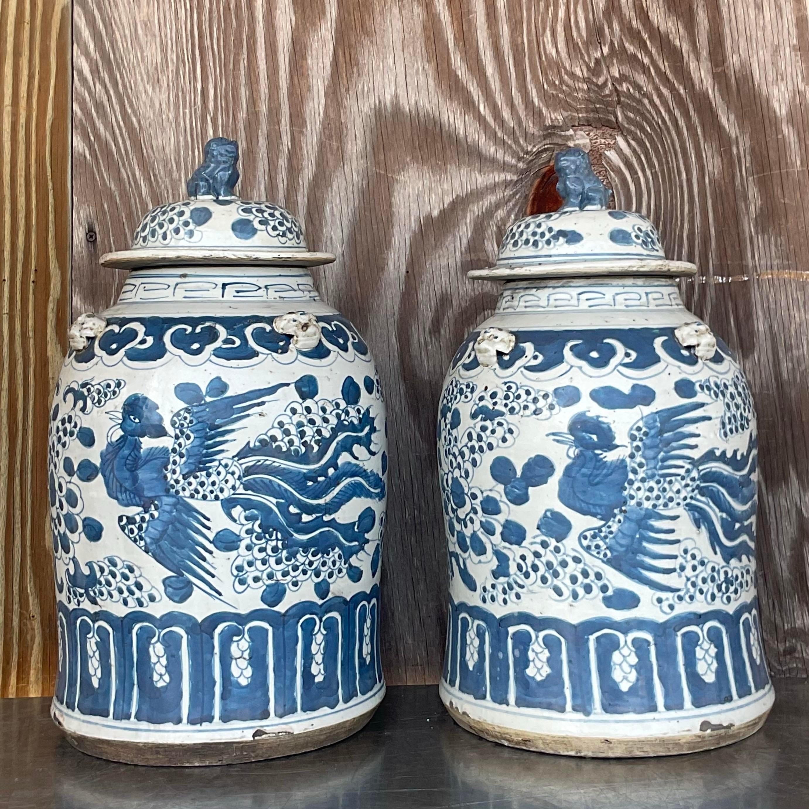A stunning pair of vintage urns. A chic Asian Pastoral design in the iconic Blue and White palate. A matte glaze over a heavy pottery vessel. Totally stunning. Acquired at a Palm Beach estate.