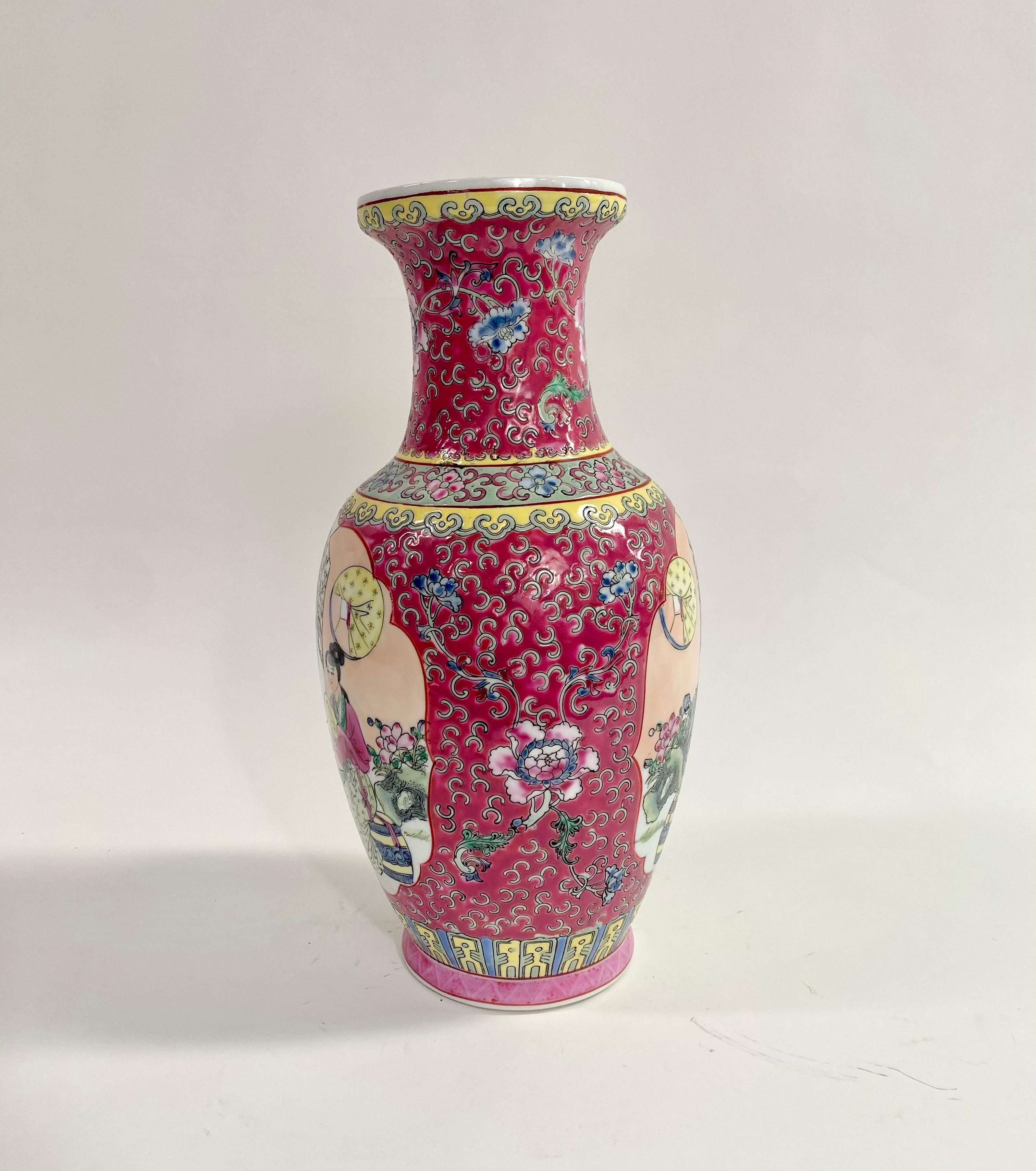 A vintage oriental Chinese export ceramic vase. The hand-painted vase depicts a scene of Three Asian women enjoying their time in a beautiful garden. The vase feature a vivid pink color background with green and yellow motifs making it standout. The
