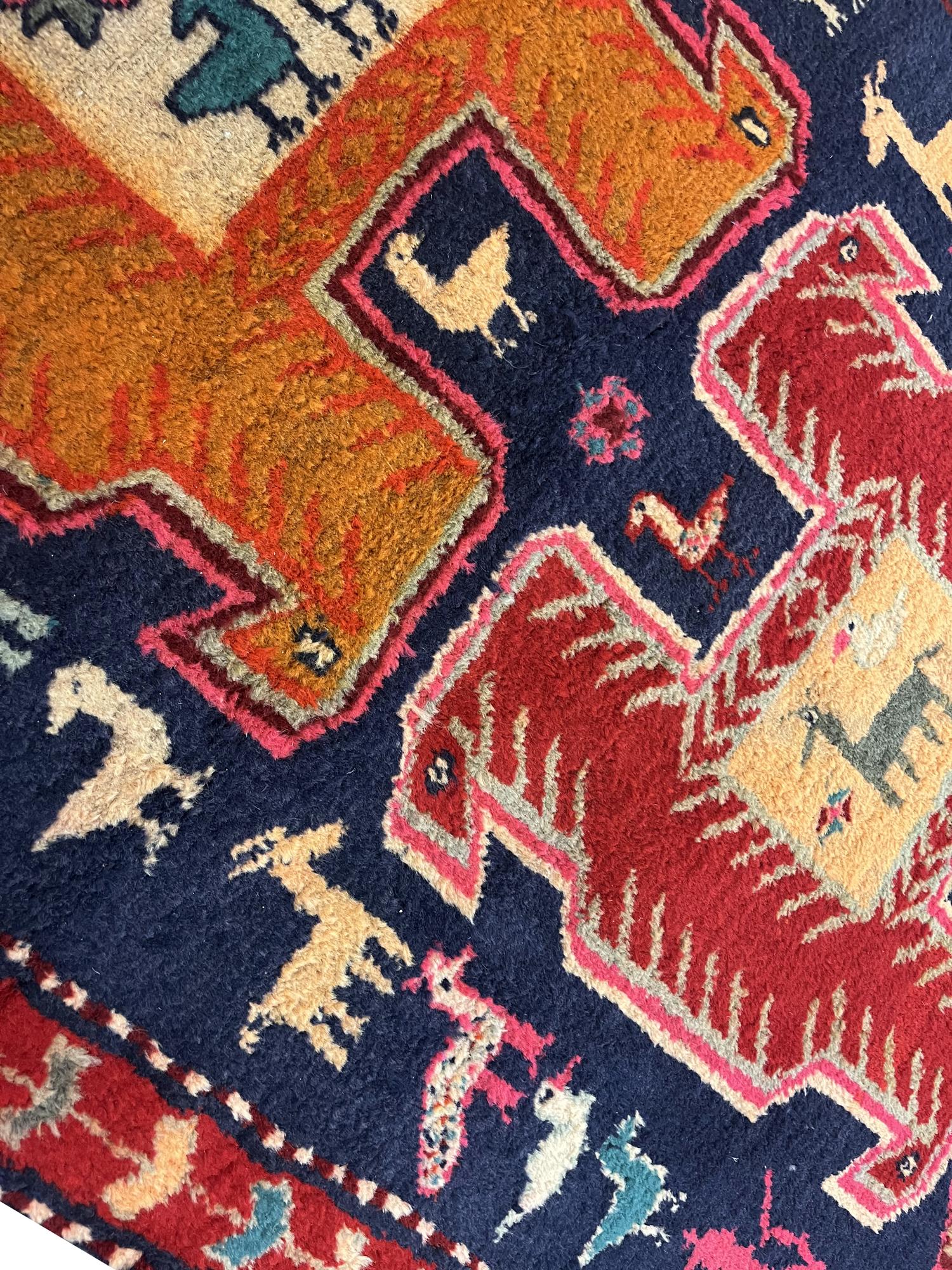 This oriental wool runner rug is an excellent example of tribal carpets woven in the 1960s. The design features a traditional medallion design, woven on a deep blue background with accents of red, rust, green and beige. The conventional design and