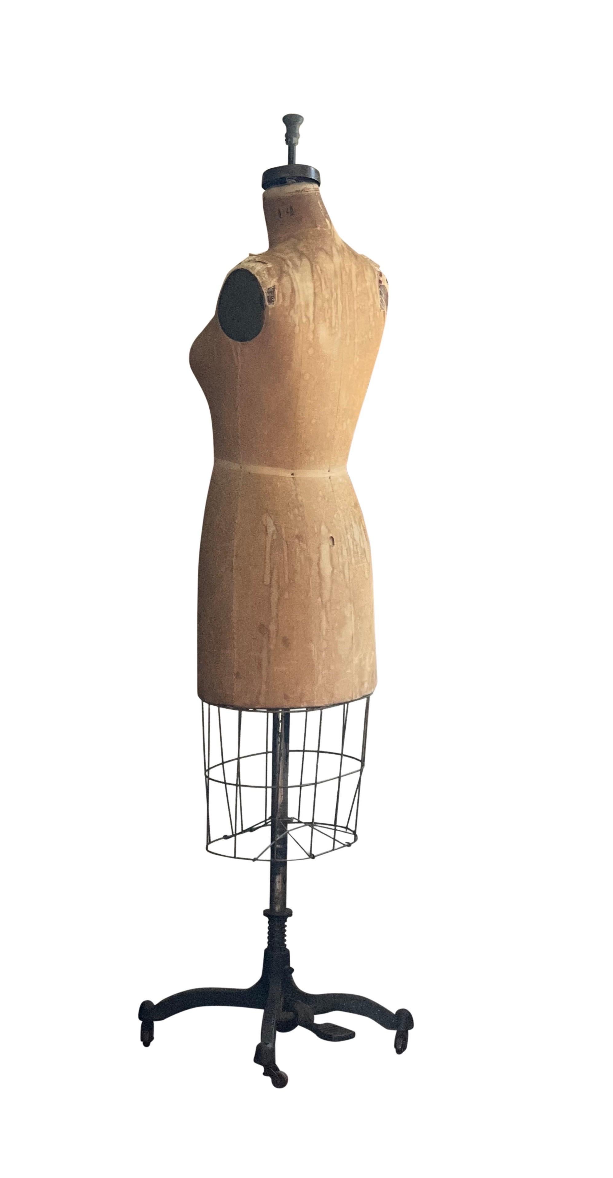 Vintage original Wolf 1956 dress form mannequin, New York.

Well worn Benjamin model dress form mannequin in size 14 on a cast iron base with casters. The form is wrapped in linen and layered with cotton batting over a papier-mâché base, machine