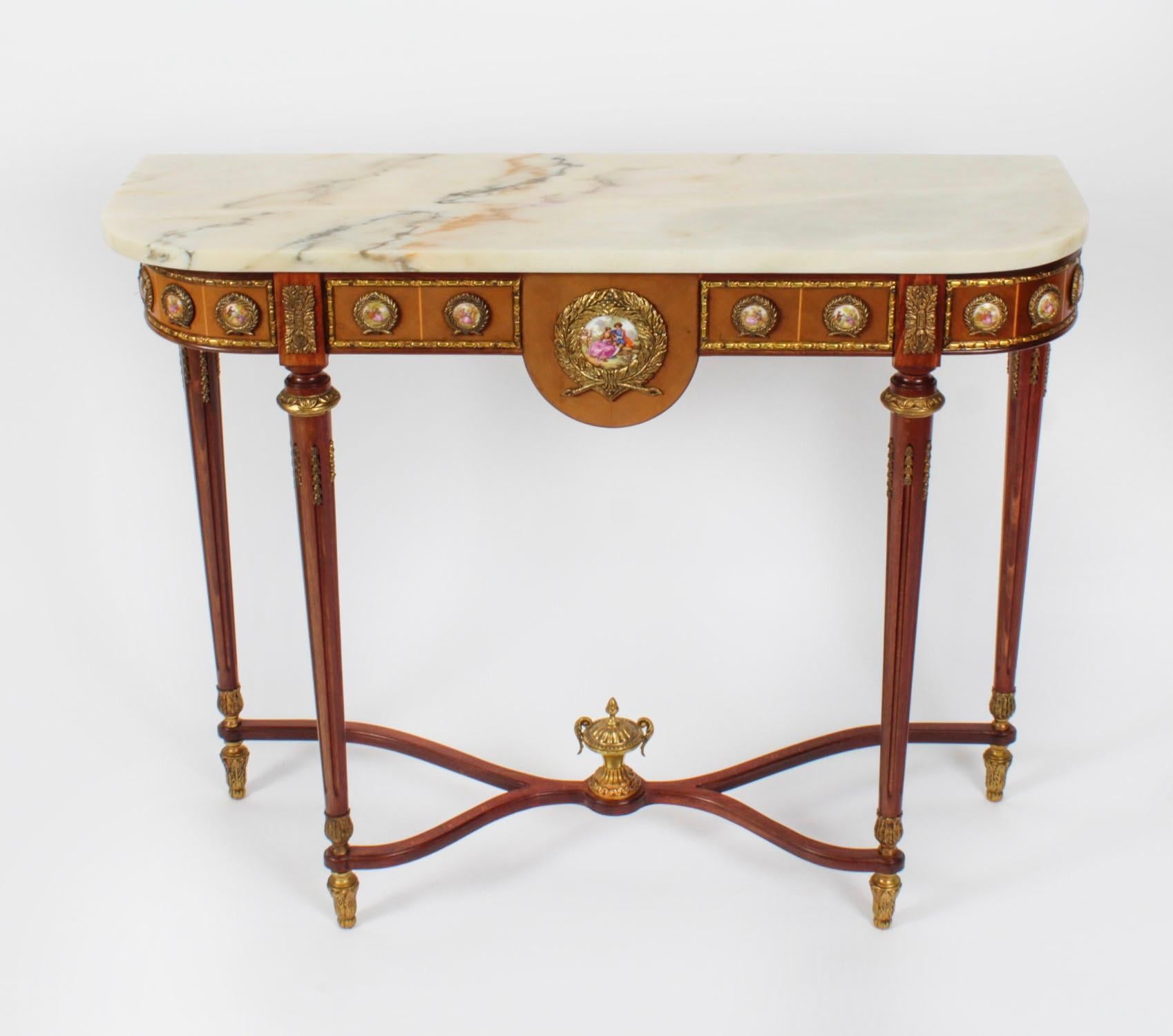 This is an elegant Louis Revival console table by the renowned cabinet maker  H& L Epstein, dating from mid 20th century.

Crafted from  wood with stunnning ormolu mounts and featuring ten Sevres style small porcelain plaques depicting courting