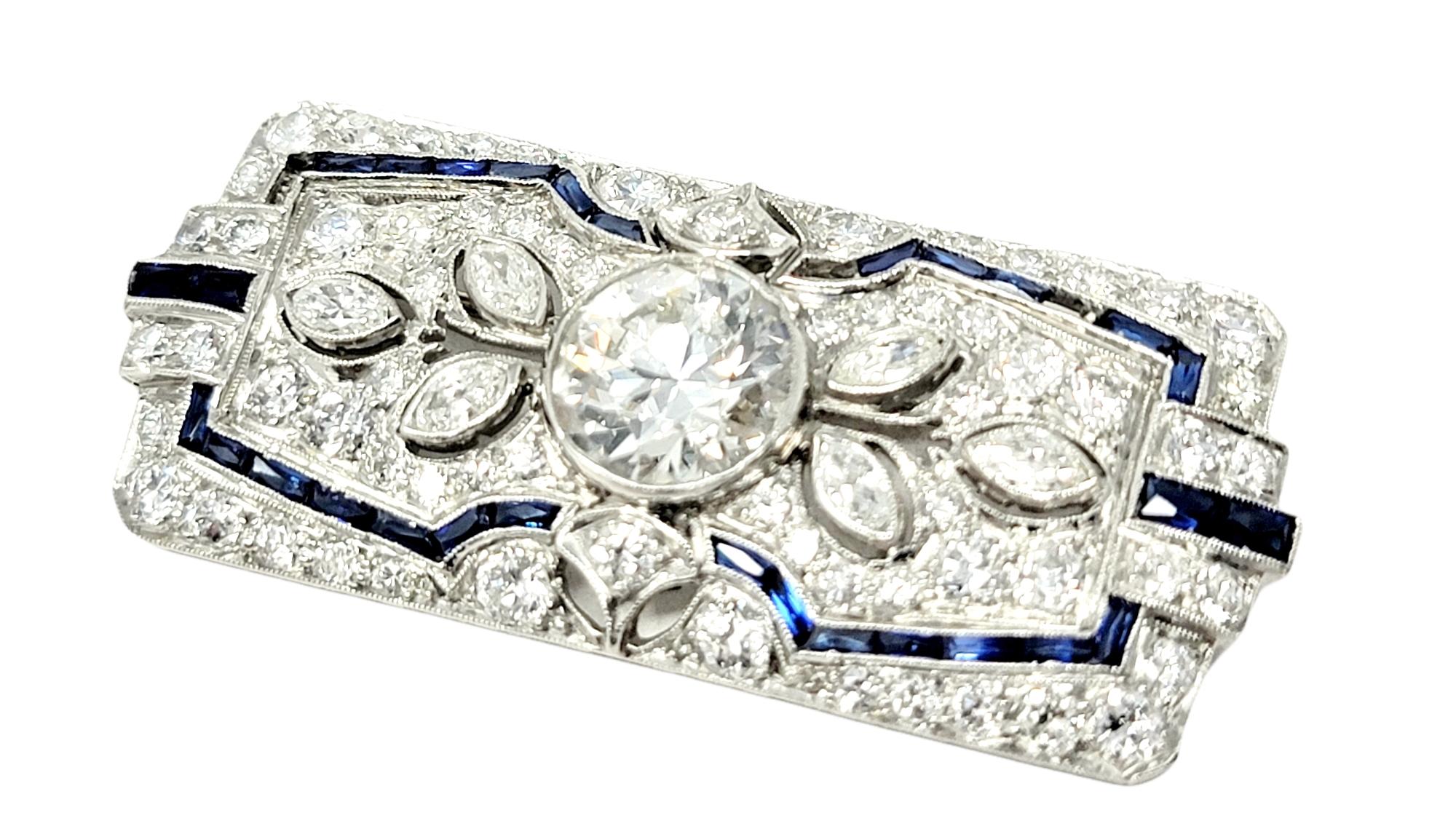 This exquisite vintage diamond and sapphire brooch is a true work of art. Stunning and shimmering, this piece is bursting with incredible sparkle and a touch of color.  The elegant platinum brooch features a sizeable bezel set early modern brilliant