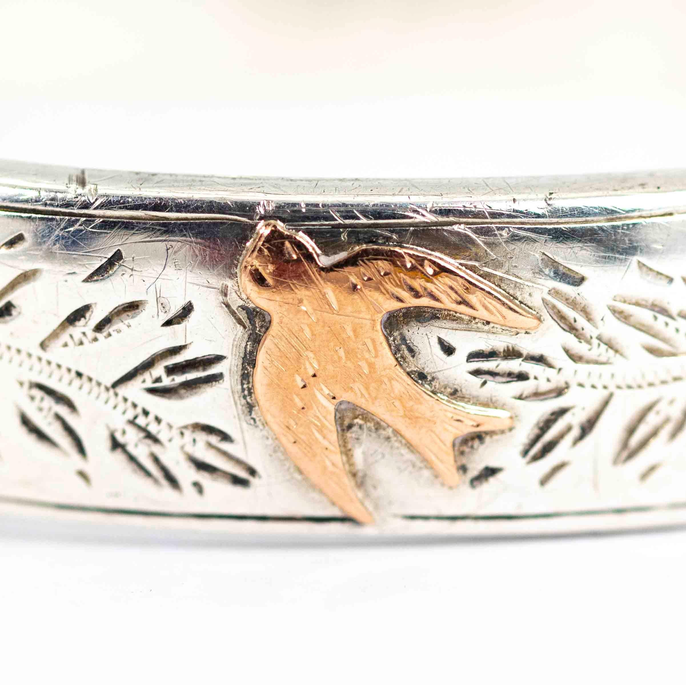 A stunning vintage 1950s bangle. The front is set with hand-chased foliate detailing between exquisite rose gold motifs of flowers and a bird. Engraved with 