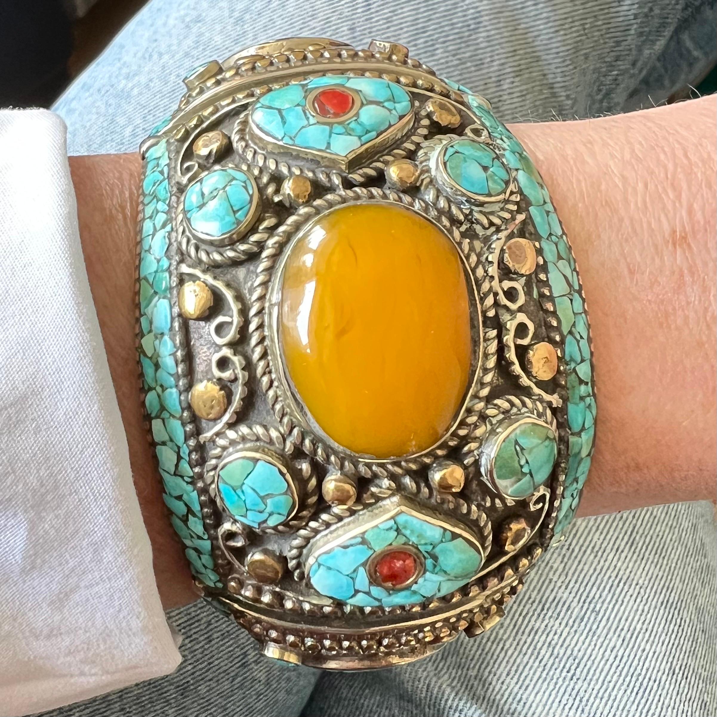 This vintage Tibetan bracelet is a bold and vibrant piece of jewelry that captures the essence of Himalayan craftsmanship. The bracelet is chunky and substantial, designed to make a statement with its striking combination of materials and