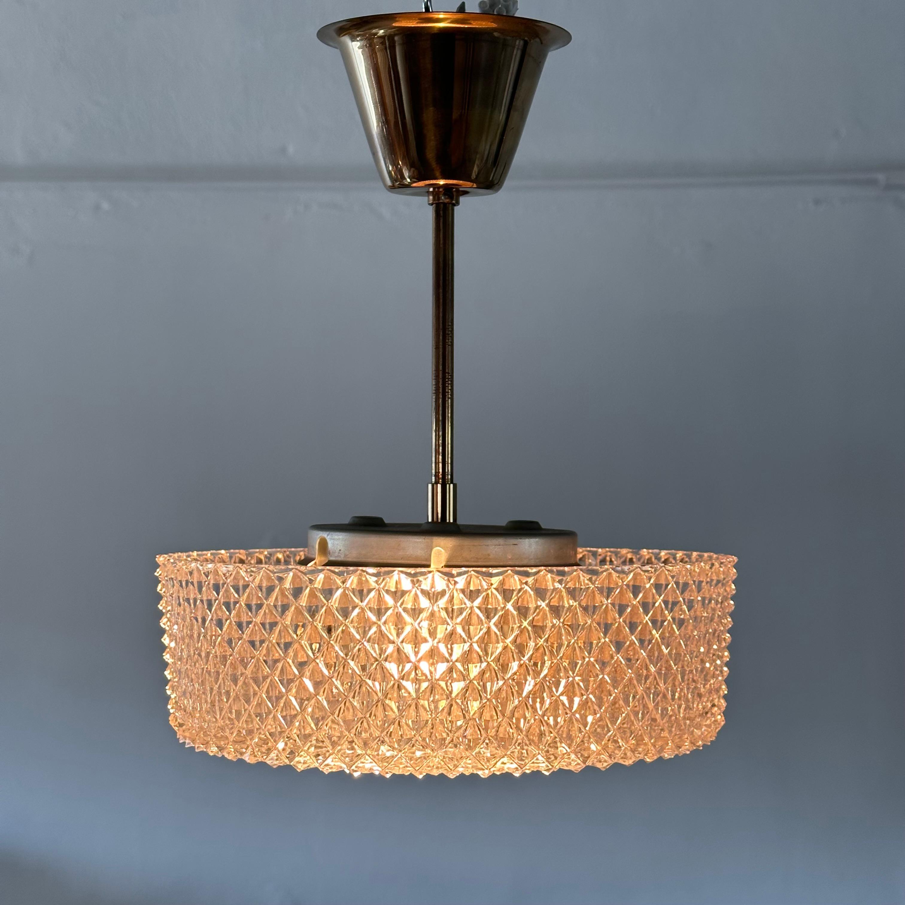 
Transform your space with the timeless allure of this vintage Orrefors Brass and Crystal Ceiling Lamp, designed by the renowned Carl Fagerlund. Crafted in Sweden during the sophisticated 1960s, this exquisite piece exudes an air of elegance and