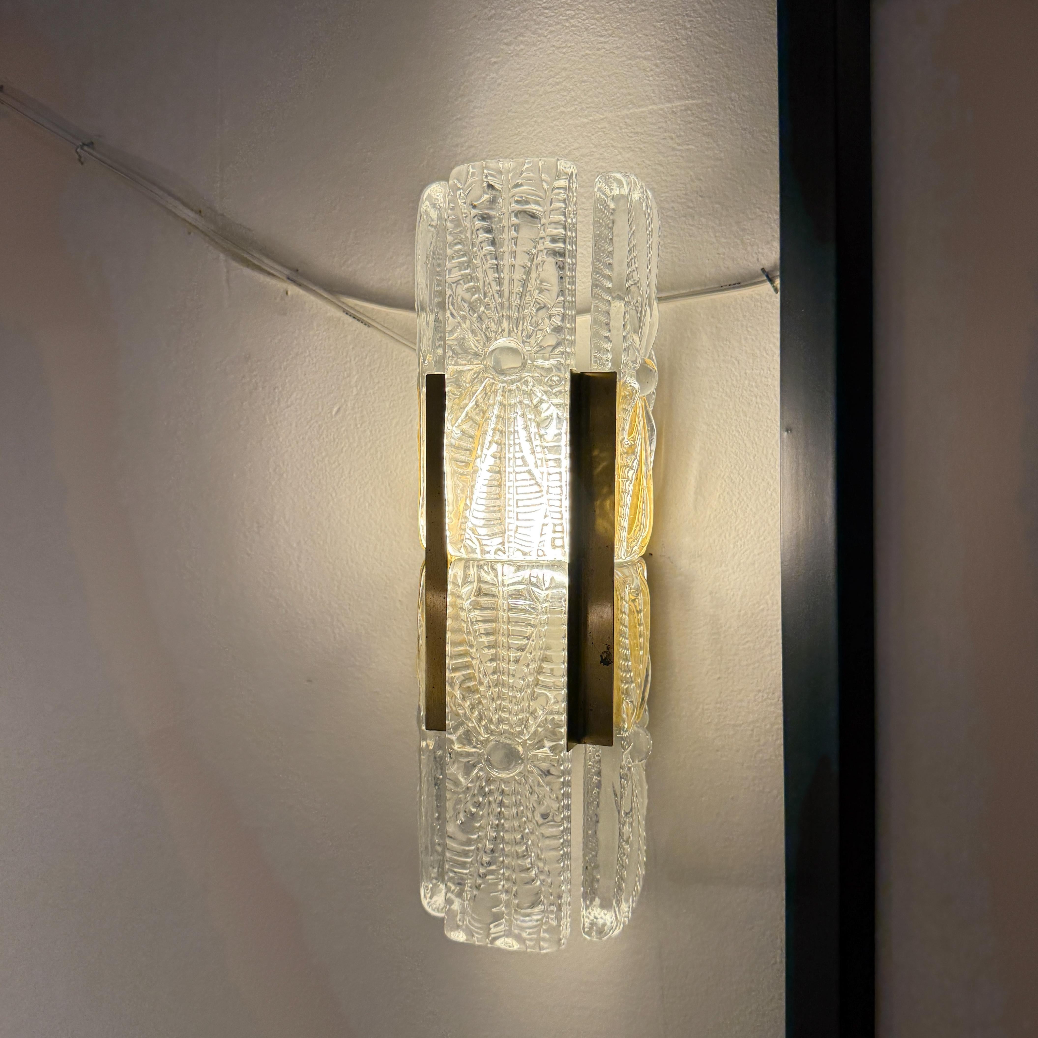 Trasforma il tuo spazio con queste lampade da parete in cristallo Orrefors Vintage. Le applique rettangolari in vetro fuso di metà secolo sono abbinate con eleganza a un corpo illuminante in ottone che include una lampadina a led da 60W. Non è