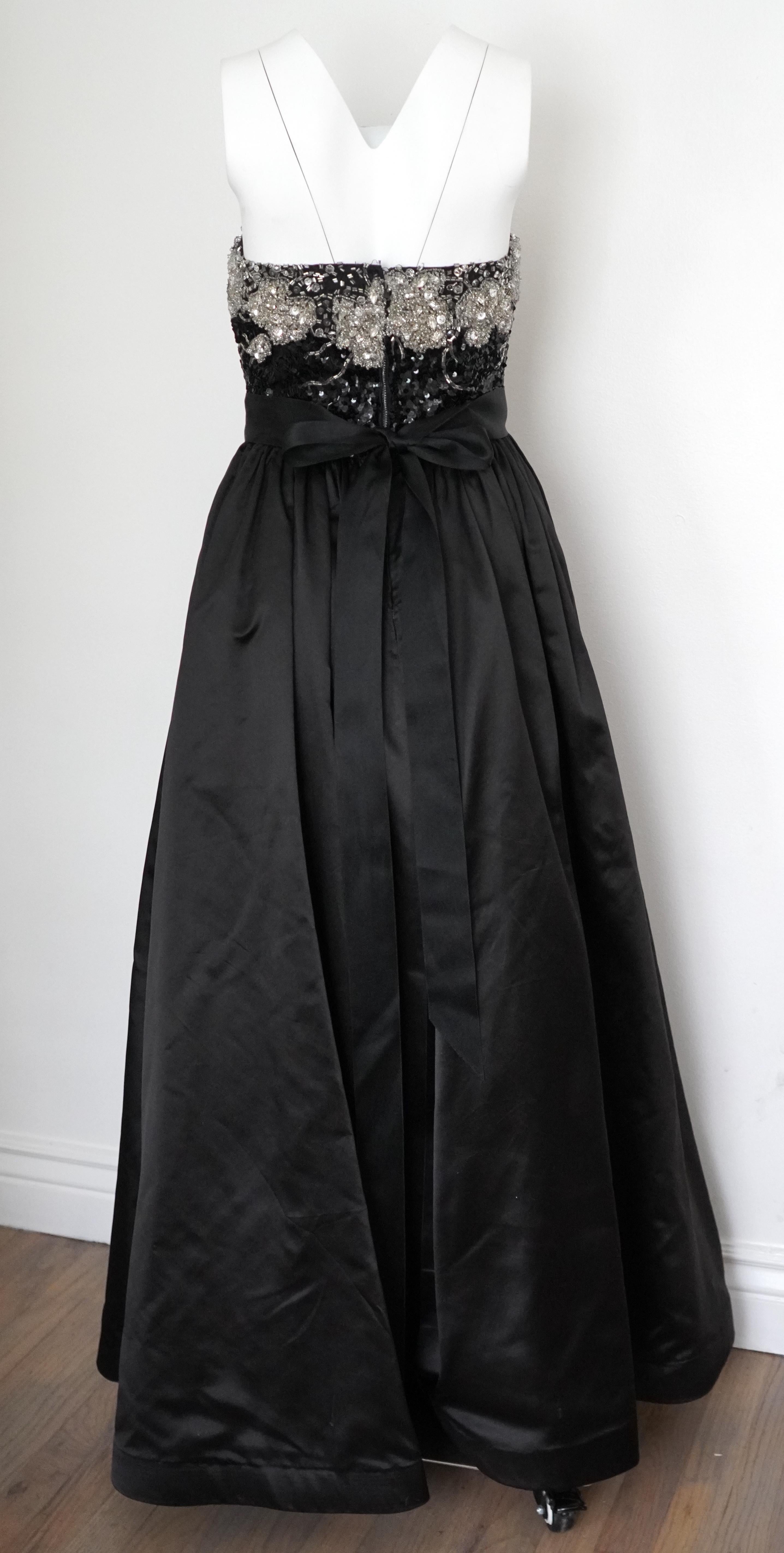The Vintage Oscar de la Renta evening gown is a true masterpiece of elegance and glamour. Crafted from luxurious black silk, this strapless gown drapes beautifully, exuding a sense of timeless sophistication. The bodice features Swarovski (silver,