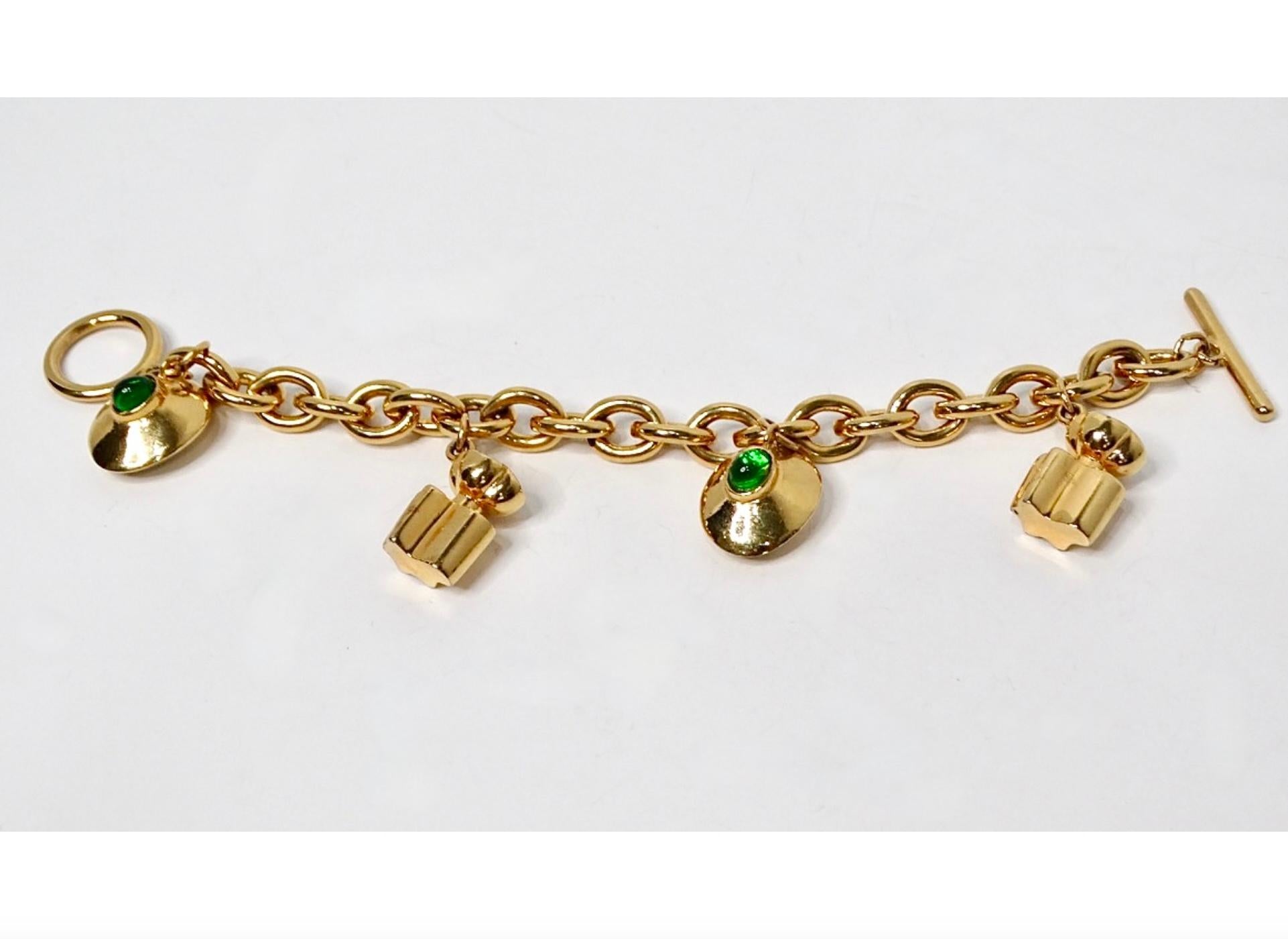 Ti presentiamo uno splendido bracciale vintage Oscar De La Renta con catene e charm in tonalità oro che incarna eleganza e raffinatezza. Questo squisito pezzo presenta deliziosi charme a forma di bottiglie di profumo e dischi rotondi, ognuno dei