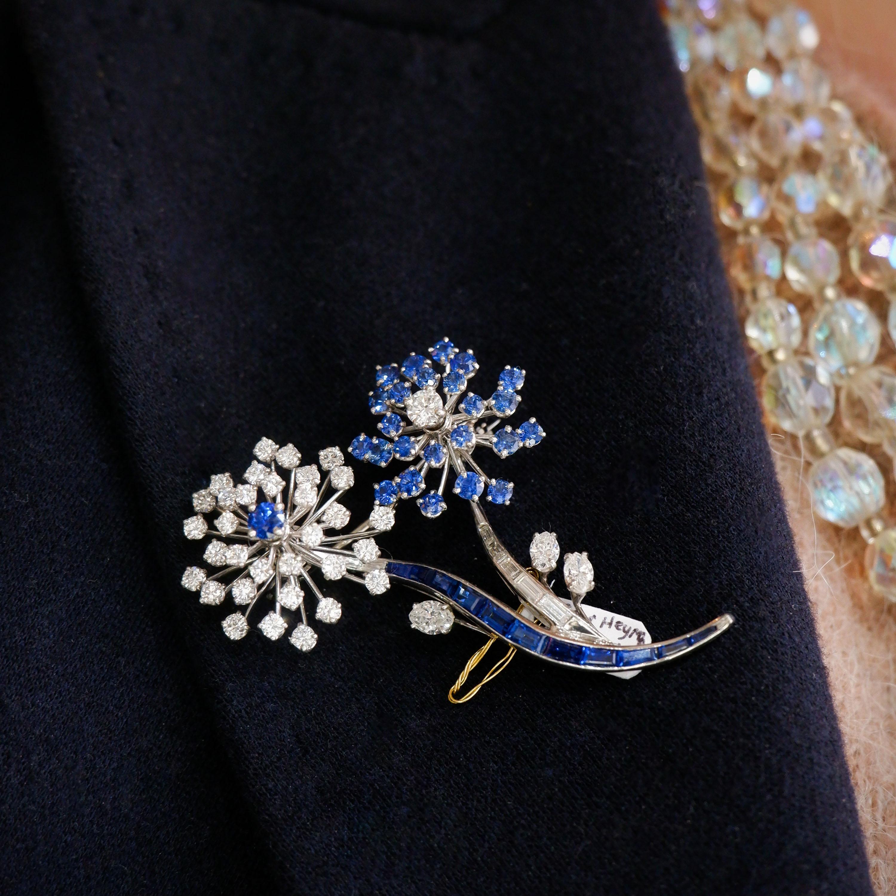 A vintage Oscar Heyman sapphire, diamond and platinum flower brooch, in an abstract design of two flowers, one with a round faceted sapphire, in the centre of round brilliant cut diamond set petals, in claw settings and a baguette-cut sapphire stem,