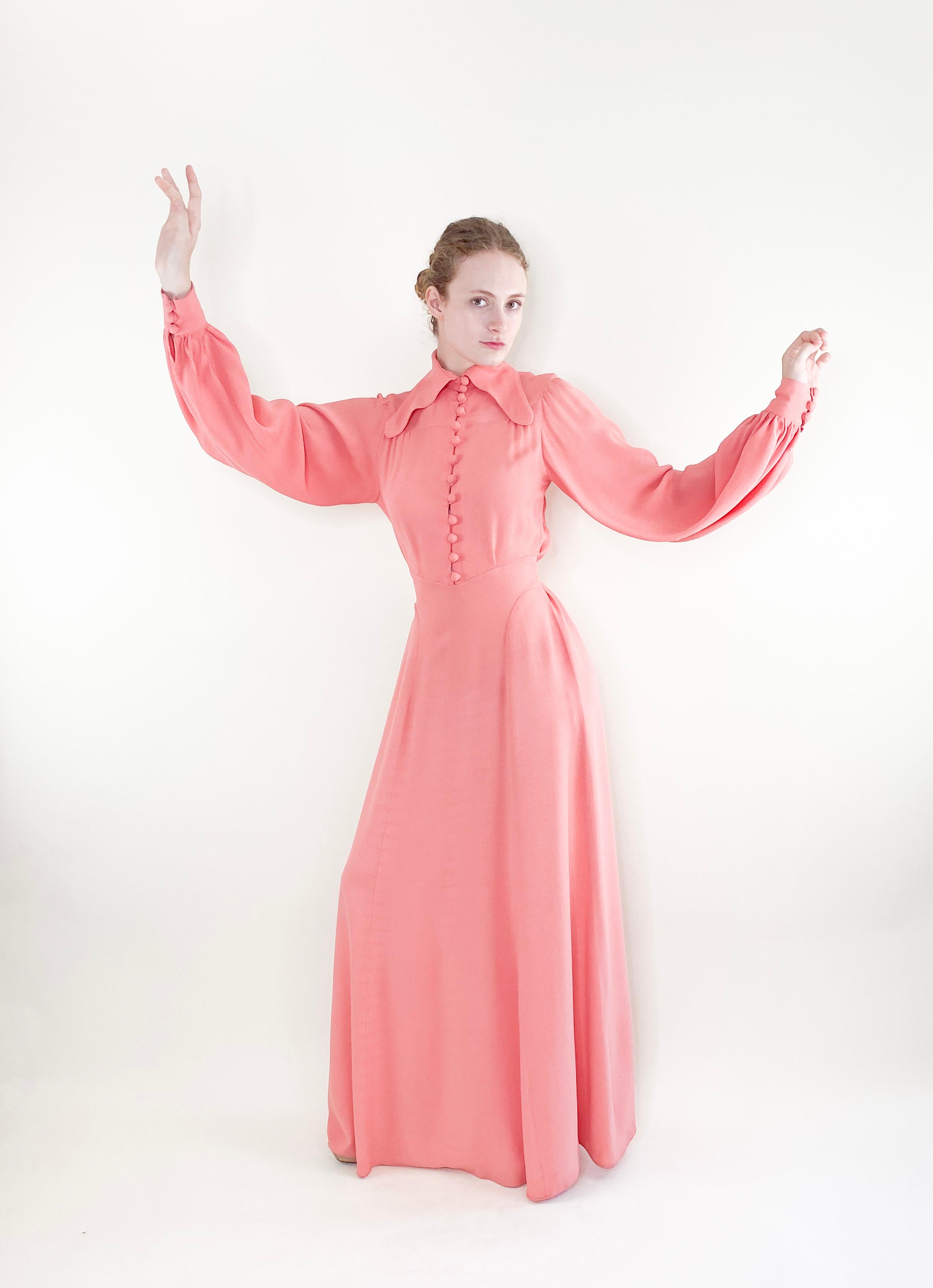 This iconic 1970's Ossie Clarke dress is a must-have for vintage lovers. Made from silky crepe fabric, this salmon pink button up dress features the designer's signature style and will add a timeless elegance to your wardrobe. 

Condition: Excellent