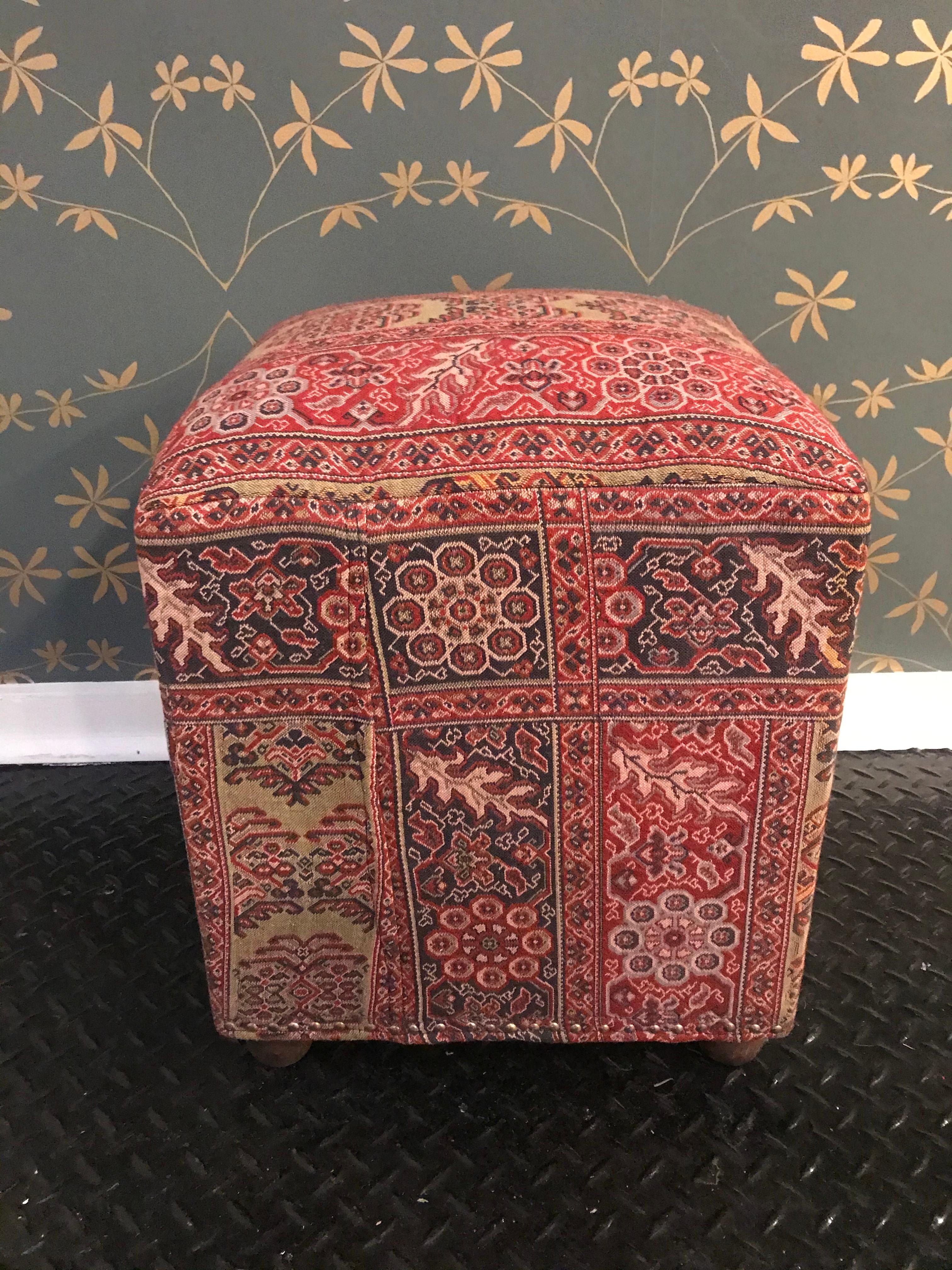 A cushioned ottoman with beautiful vintage fabric.
Decorative stapling on the bottom edge and rounded wooden legs.