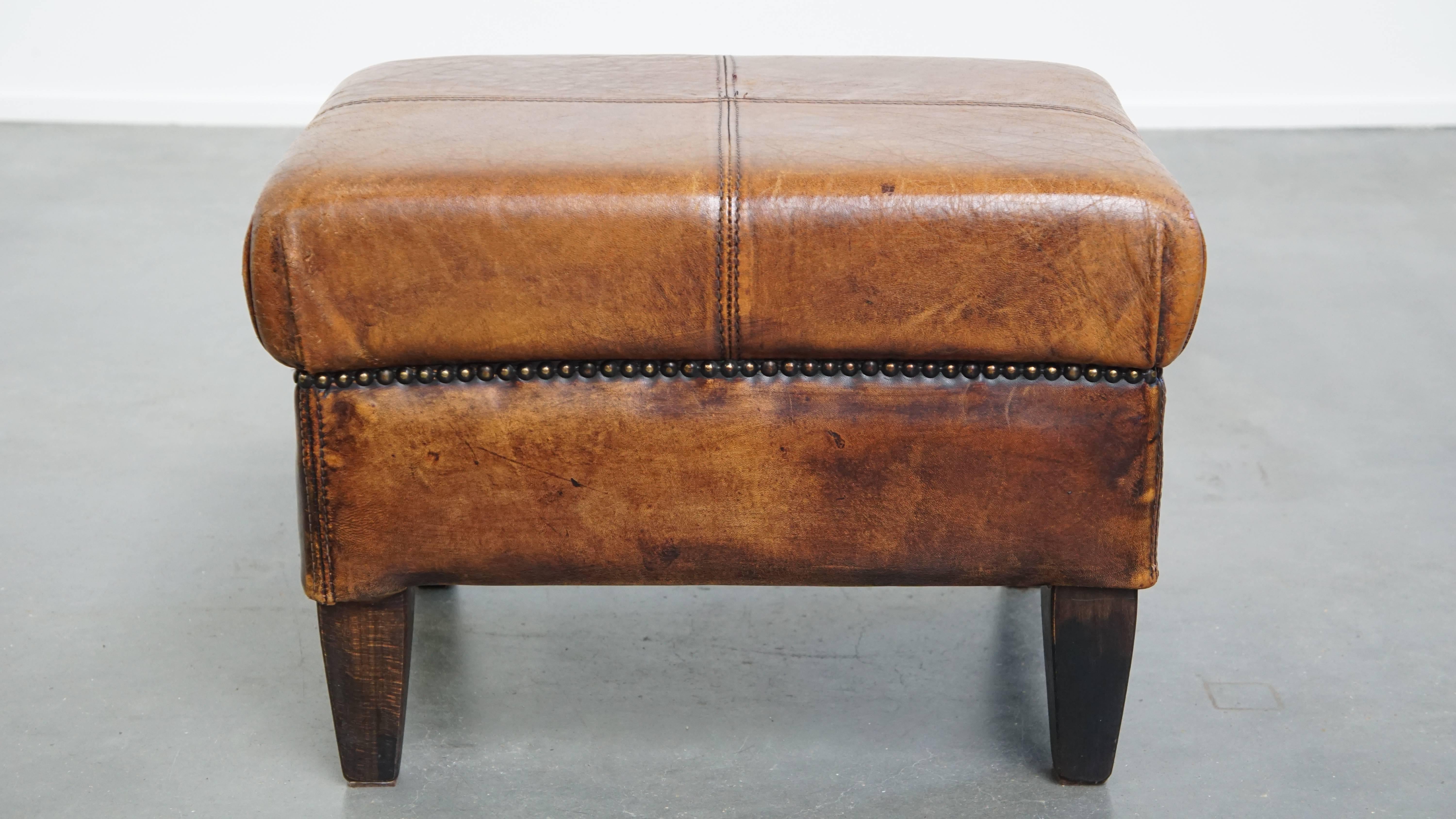 Offered is this sturdy vintage ottoman, crafted from sheepskin leather and finished with decorative nails.

A sheepskin leather footstool, also known as an ottoman, transforms your already comfortable armchair into a true relaxation paradise. With