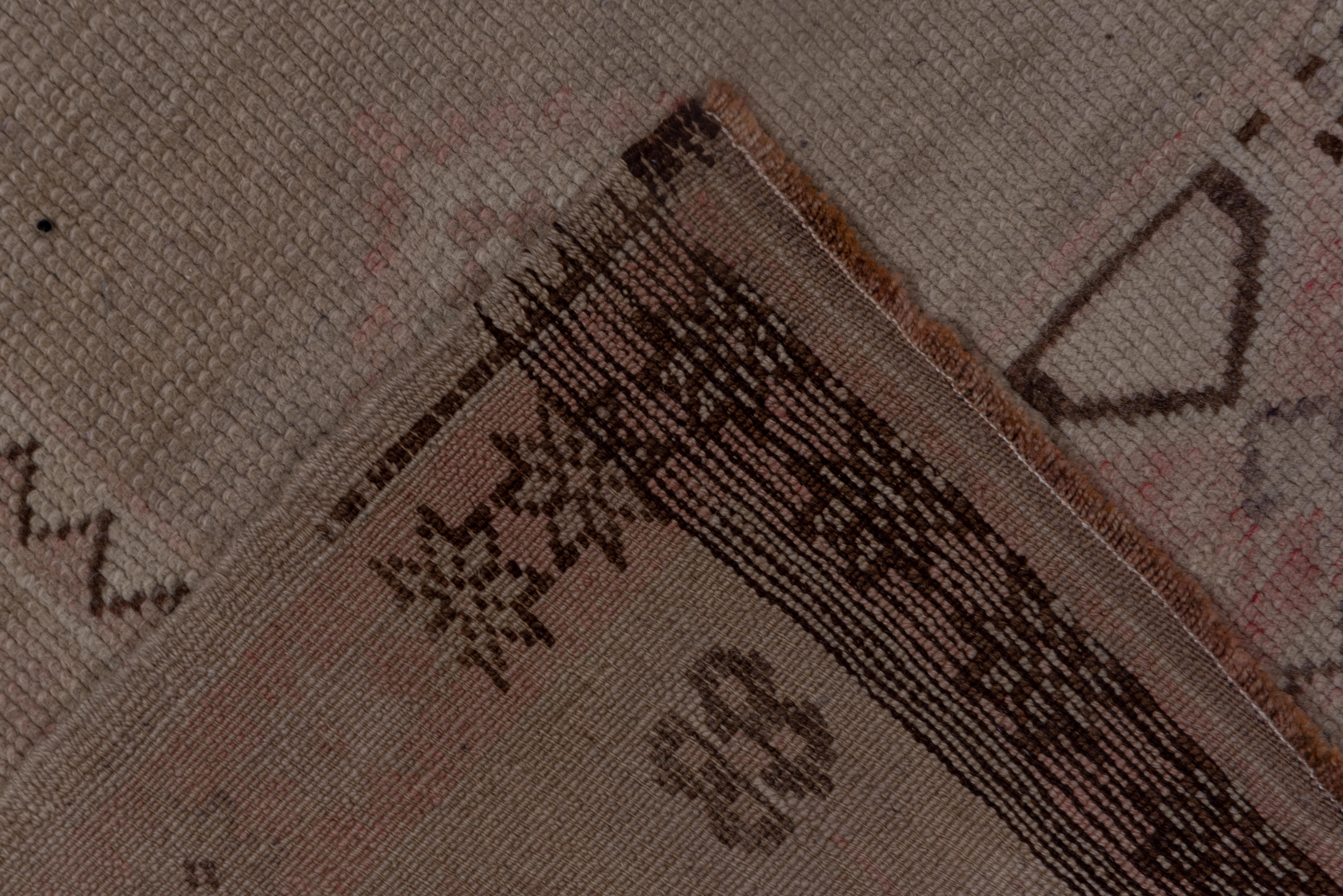 This vintage Oushak rug features a serene medallion design softened by time and rendered in delicate tones of blush, taupe, and ivory. The faded aesthetic highlights its age and character, while the geometric forms and subtle botanical motifs remain