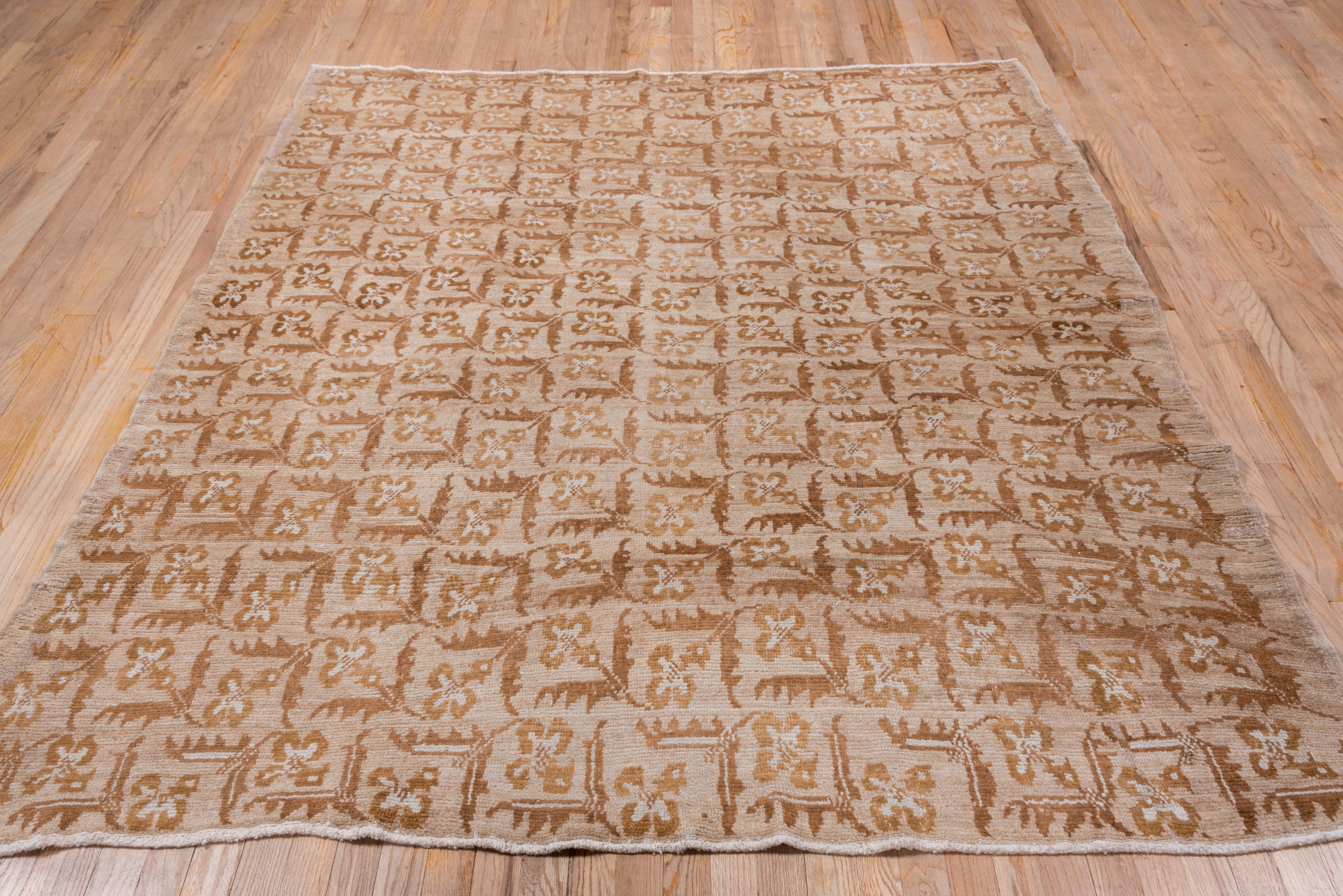 This borderless squarish Anatolian village rug displays an all-over, repeating pattern of flowers with rust-buff blossoms and olive twin serrated leaves. The flowers change vertical orientation column by column.
