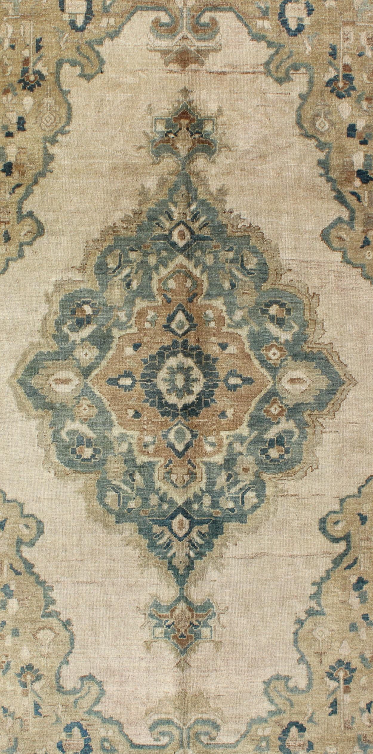 Measures: 5'2 x 9'11.

This vintage Turkish Oushak rug features a unique blend of colors and an intricately beautiful design. The multi-layered central medallion is complemented by a symmetrical set of floral motifs in the field and surrounding