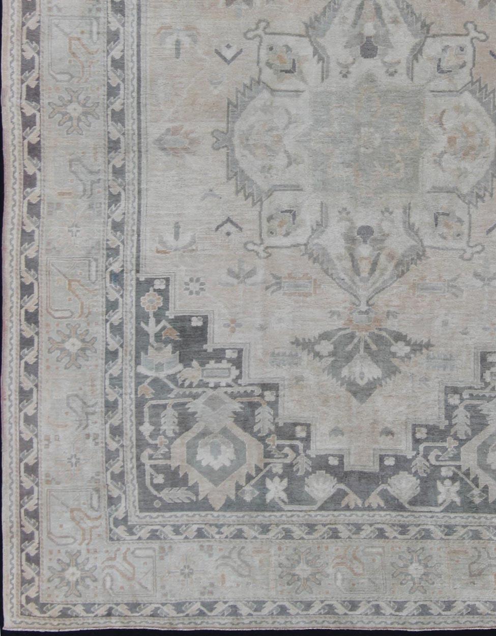 Light and mid-toned neutrals vintage Oushak carpet in grays and soft colors, rug en-115259, country of origin / type: Turkey / Oushak, circa 1940

This vintage midcentury Turkish Oushak displays a sub-geometric medallion in its center, with