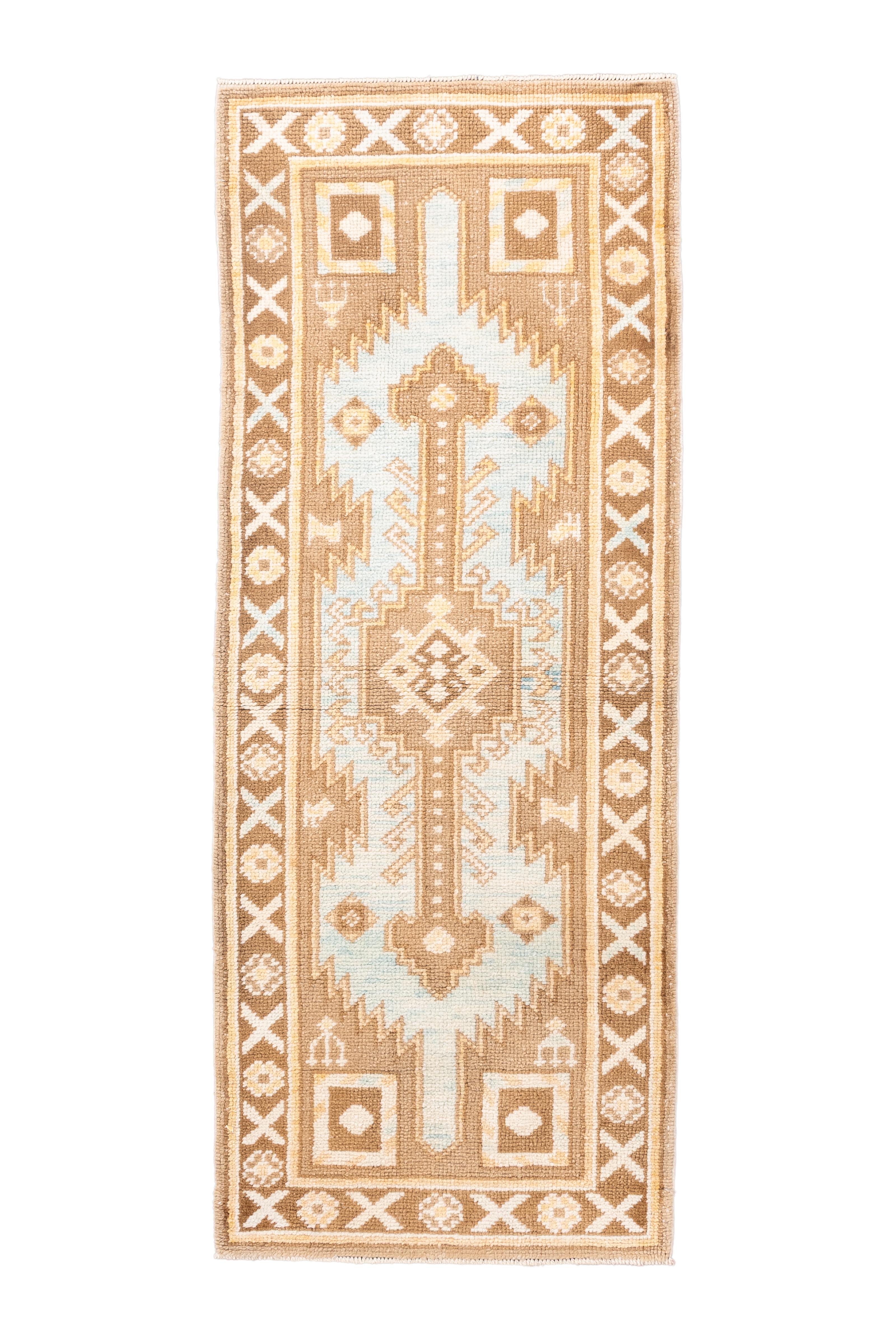  Un affascinante runner Oushak vintage, annodato a mano in Turchia, caratterizzato da un medaglione tribale angolare affiancato da motivi floreali e geometrici stilizzati. La tavolozza è particolarmente invitante: le calde tonalità del cammello