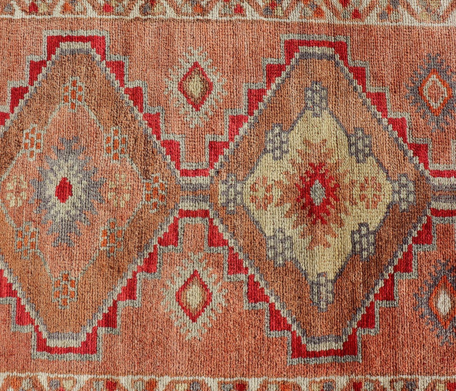 Measures: 2'10 x 11'10
Vintage Turkish Oushak Runner with Tribal Medallions in Redish Tones. Keivan Woven Arts / rug TU-NED-4688, country of origin / type: Turkey / Oushak, circa 1950.
This vintage Oushak runner features a unique blend of cheerful