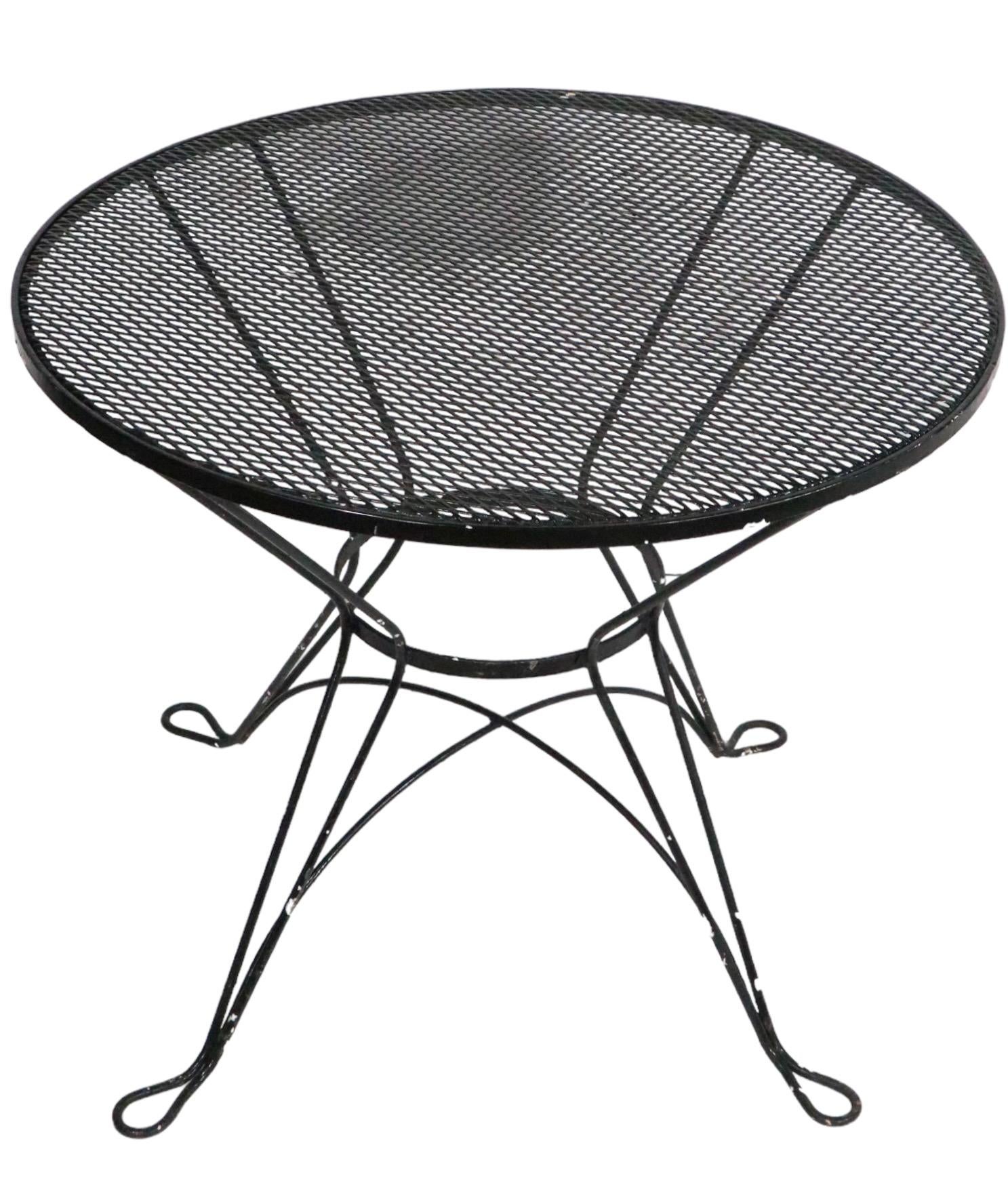 Chic architectural garden, patio, poolside dining, cafe style table in wrought iron and metal mesh. The table has a circular metal mesh top ( 35 in. Dia.)  which is mounted on a waisted form iron  pedestal base. It is in very good, original, clean