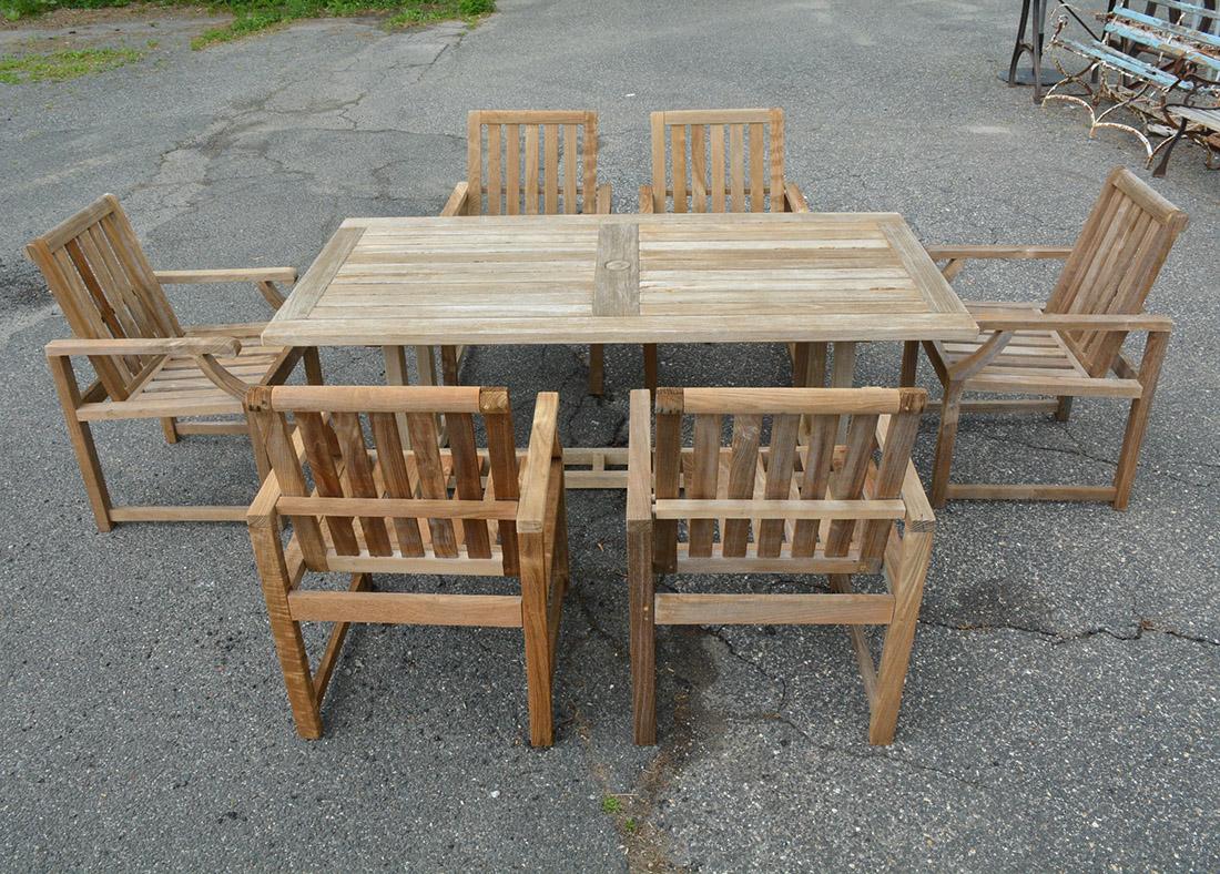 Vintage outdoor teak wood dining set seats 6. This patio, porch or garden rectangular dining table has a center cutout at center for an umbrella and 6 armchairs. Chairs have generous proportions for comfortable seating. Set has been recently cleaned