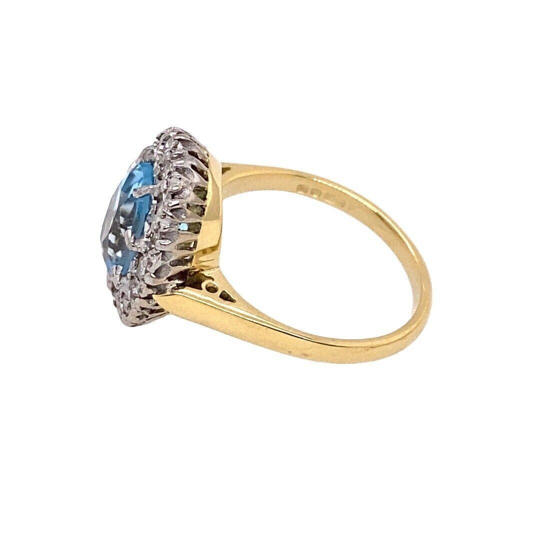 Cette magnifique bague présente une topaze bleue ovale, entourée de 16 diamants ronds de taille brillant. La bague est réalisée en or jaune et blanc 18ct,
et s'inscrit dans un style vintage qui est l'incarnation de l'élégance