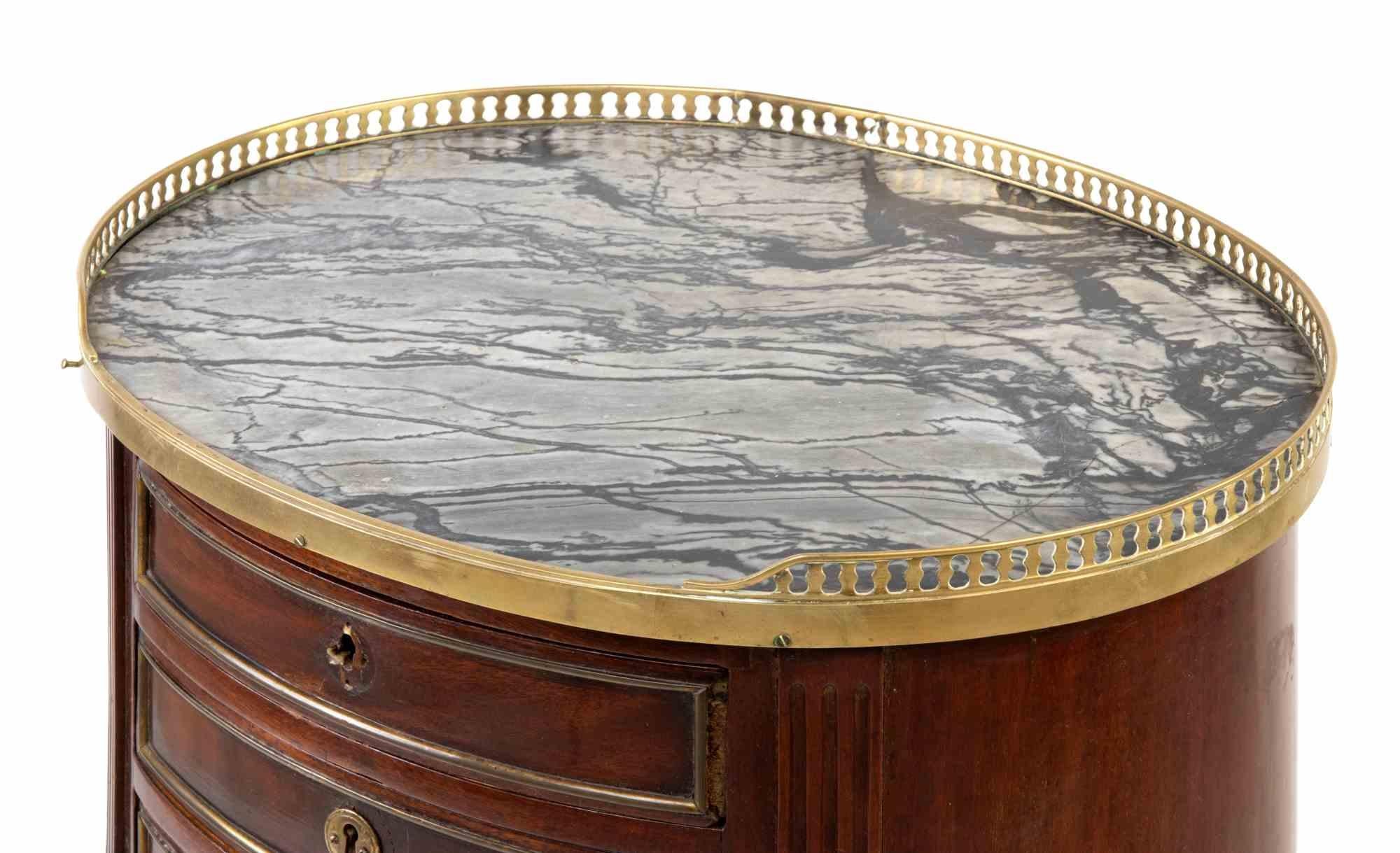 Le chevet ovale Vintage est un objet de design réalisé au début du 20ème siècle.

Centre de table de forme ovale en acajou avec filets en métal doré, plateau en marbre avec balustrade, 3 tiroirs et 4 pieds reliés par une tablette