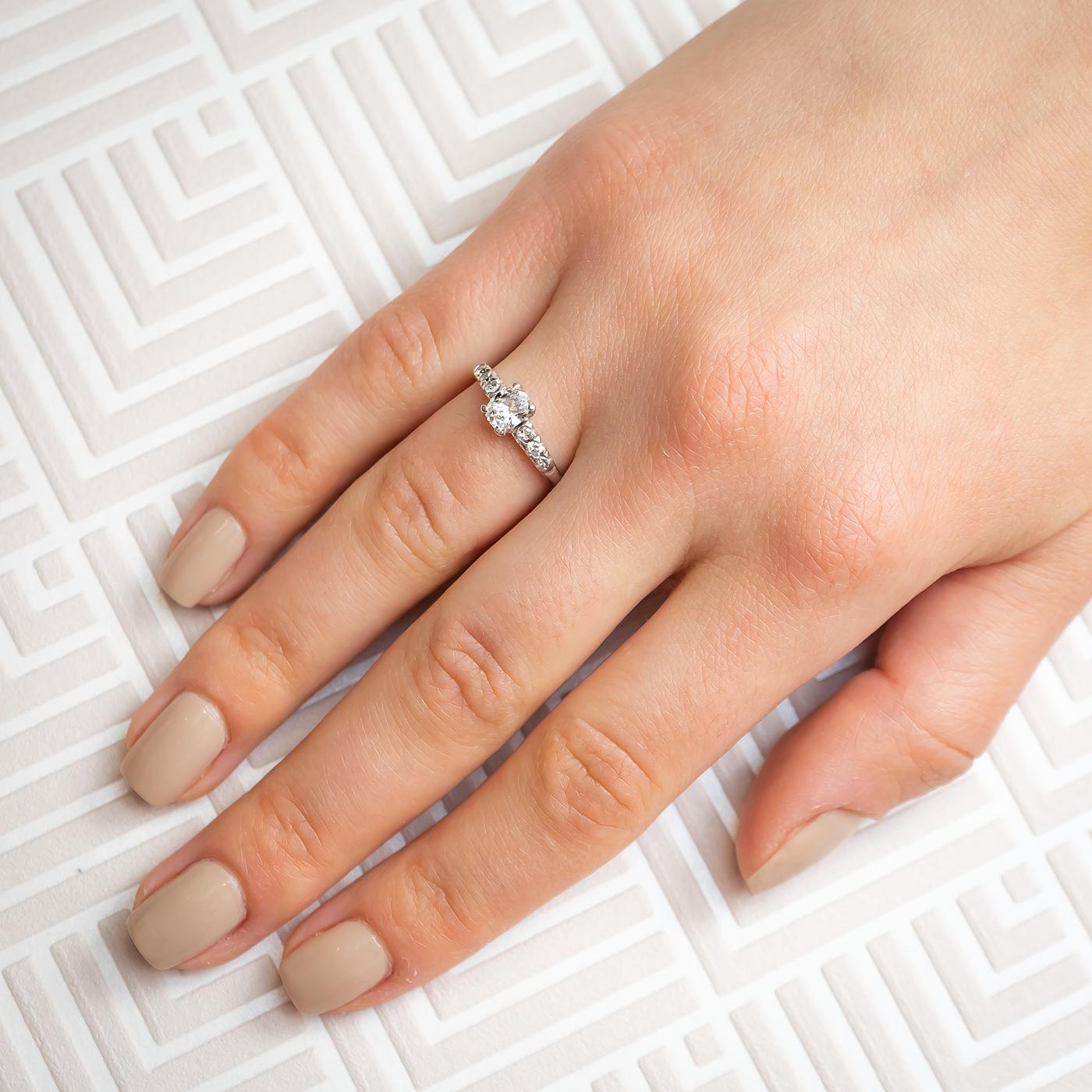A vintage diamond ring, set with a 0.51 carat, D colour, VS1 clarity, oval brilliant-cut diamond, in a four claw setting,  with three small round brilliant-cut diamonds set in each shoulder, in four claw illusion settings, mounted in platinum.