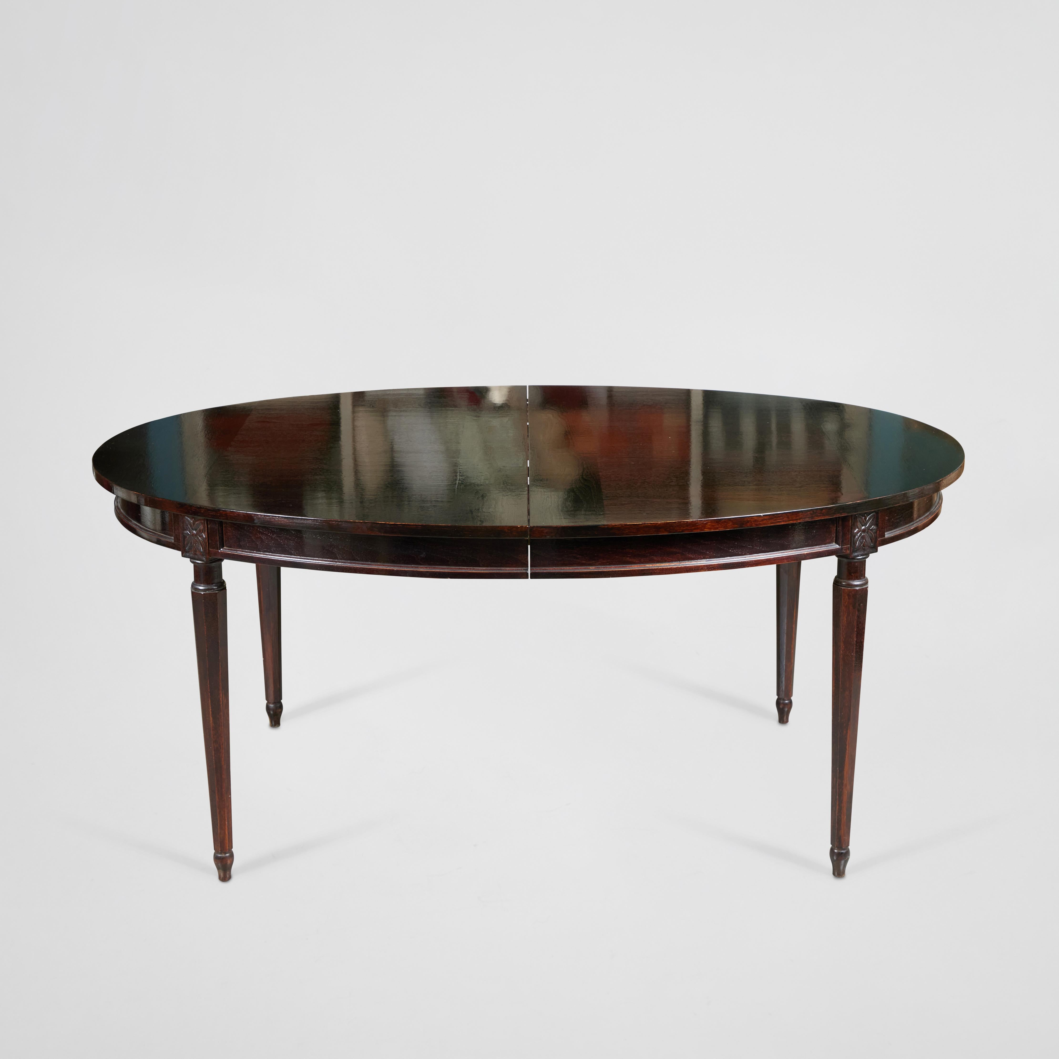Charming vintage oval extension dining table has its original shiny espresso lacquer finish. This table has carved decorative floral medallions on the apron and beautiful ornamental legs. It comes with 2 - 18