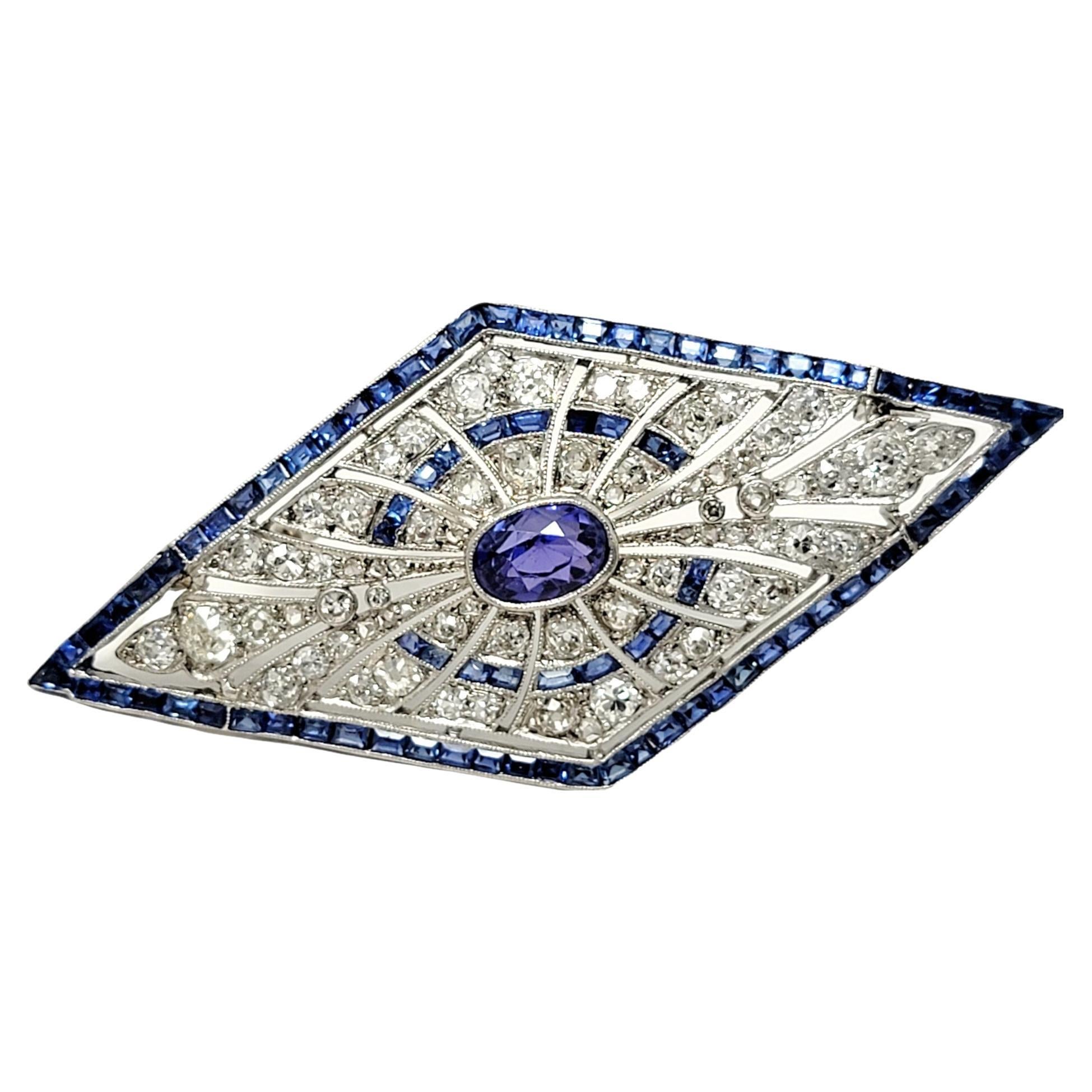 This exquisite vintage sapphire and diamond brooch is a true work of art. This stunning, shimmering piece is bursting with both color and sparkle.  The elegant platinum brooch features an incredible bezel set oval mixed cut natural sapphire in a