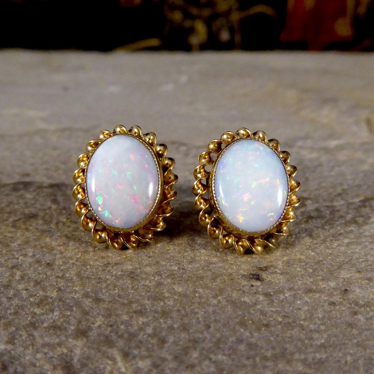 These lovely classic earrings have been fully crafted from 9ct Yellow Gold with hallmarks down the stem showing they were made in Birmingham. These earrings hold an oval shaped Opal in each stud showing lovely colours in a collar setting, a perfect
