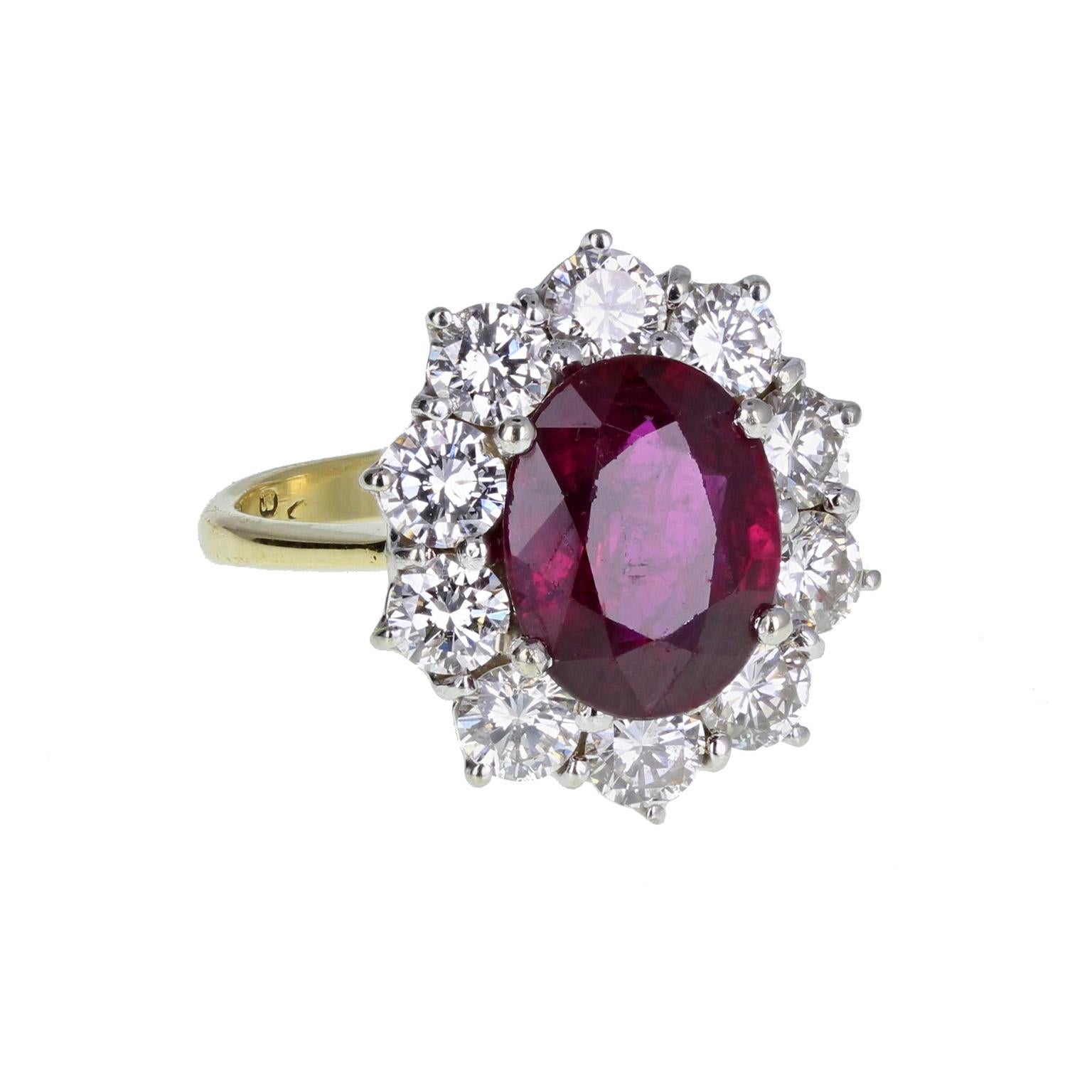 A fine and impressive oval cluster ring. A central oval brilliant-cut blood-red ruby, mounted in four claws, surrounded by ten round, brilliant-cut diamonds. 18-carat yellow gold shank with tapering shoulders, hallmarked London 1994. Ruby Weight:
