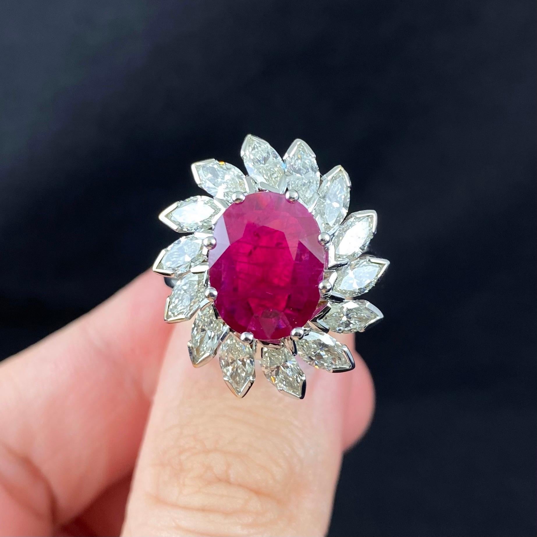 Vintage Oval Ruby and Marquise Brilliant Cut Diamond Floral Coronet Cluster Engagement Ring in 19.2 Karat White Gold, Portugal, 1980s/1990s. This jewel features an intense purplish red oval mixed-cut ruby eight claw-set to the centre, surrounded by