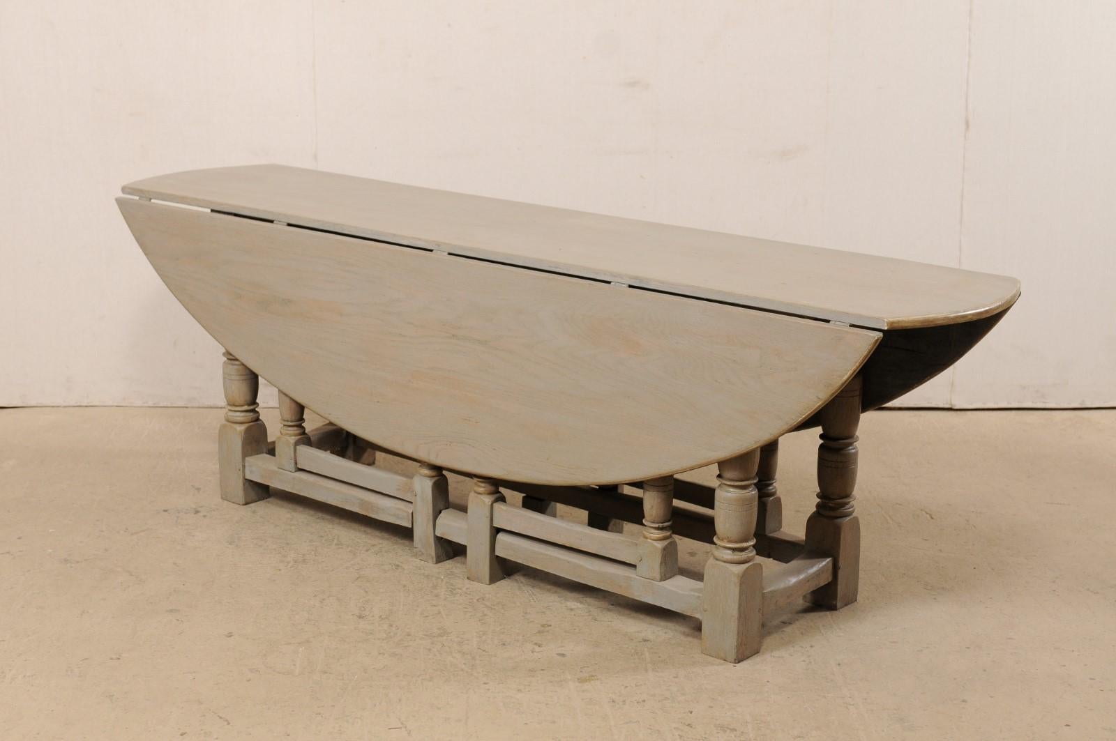 An American painted wood drop leaf and gate-leg table. This vintage oval-shaped table features two drop leaf sides, than when down, make this nicely sized oval table, a more slender 21.5