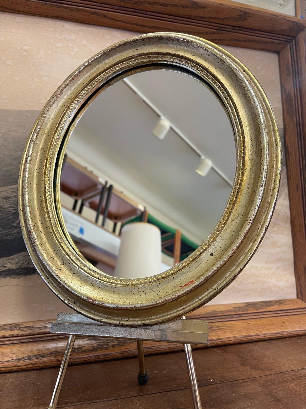 Oval  shaped small wall Mirror with gold toned painted wood framing. Stand not included. Vintage Condition Consistent with Age as Pictured.

Dimensions. 11 W ; 1 D ; 13 H