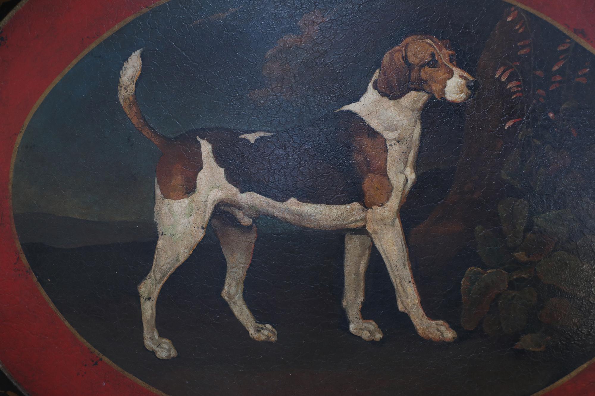 Vintage oval tole serving tray with a central portrait of a beagle in an outdoor setting surrounded by a dark red border with a shallow lip with gold and black painted design with two cut out handles.