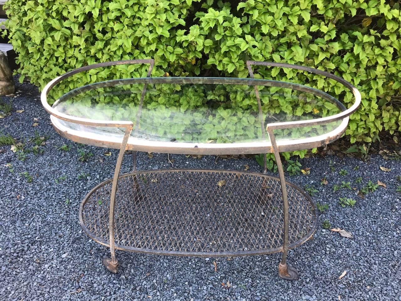 A vintage Woodard wrought iron bar cart by Woodard, having new glass top tier and a lattice iron bottom tier, on wheels for easy moving. Great for the outside deck or patio.
Table has been left in original slightly rusty condition, great bones but