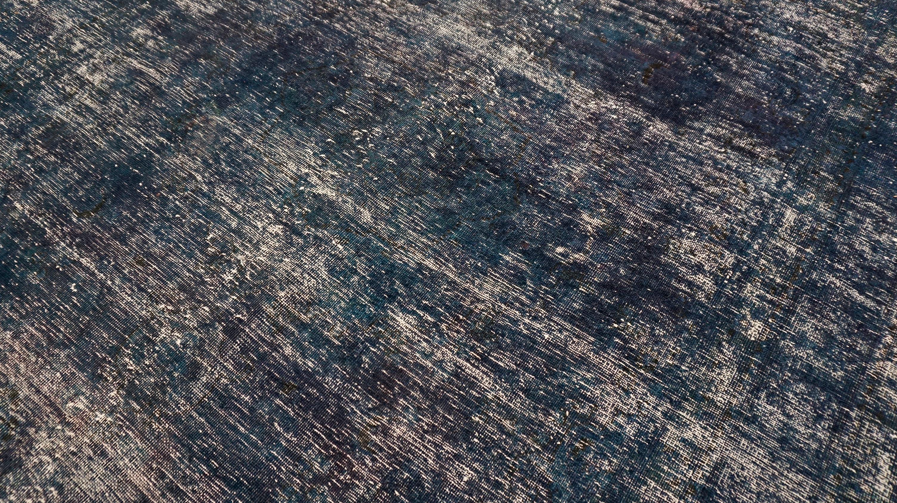 Questo tappeto in lana annodato a mano è un'espressione magistrale di arte moderna, con un motivo astratto riccamente stratificato in un profondo indaco di mezzanotte con sfumature grigie. La composizione mescola una texture pittorica con una