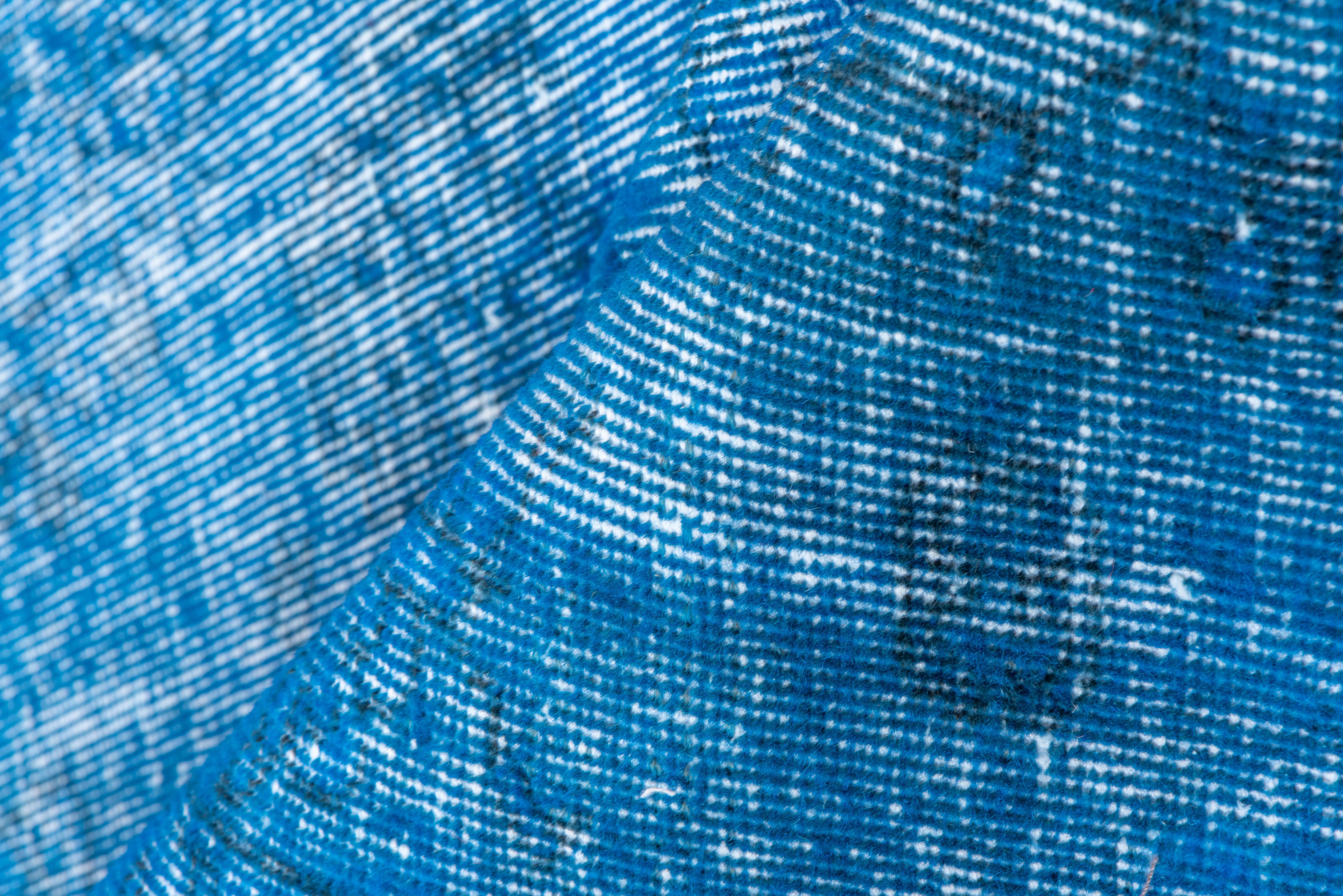 Dieser blaue türkische Overdye-Teppich hat ein Muster, das durch die Abnutzung jenseits der allgemeinen Notlage definiert ist. Vertikale und horizontale, gebrochen weiße Streifen kreuzen sich in der Nähe der Mitte. Shabby-Chic-Bedingungen und kann